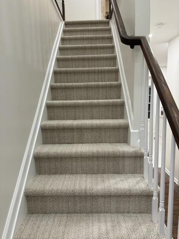 a set of stairs with carpeted steps and a wooden railing .
