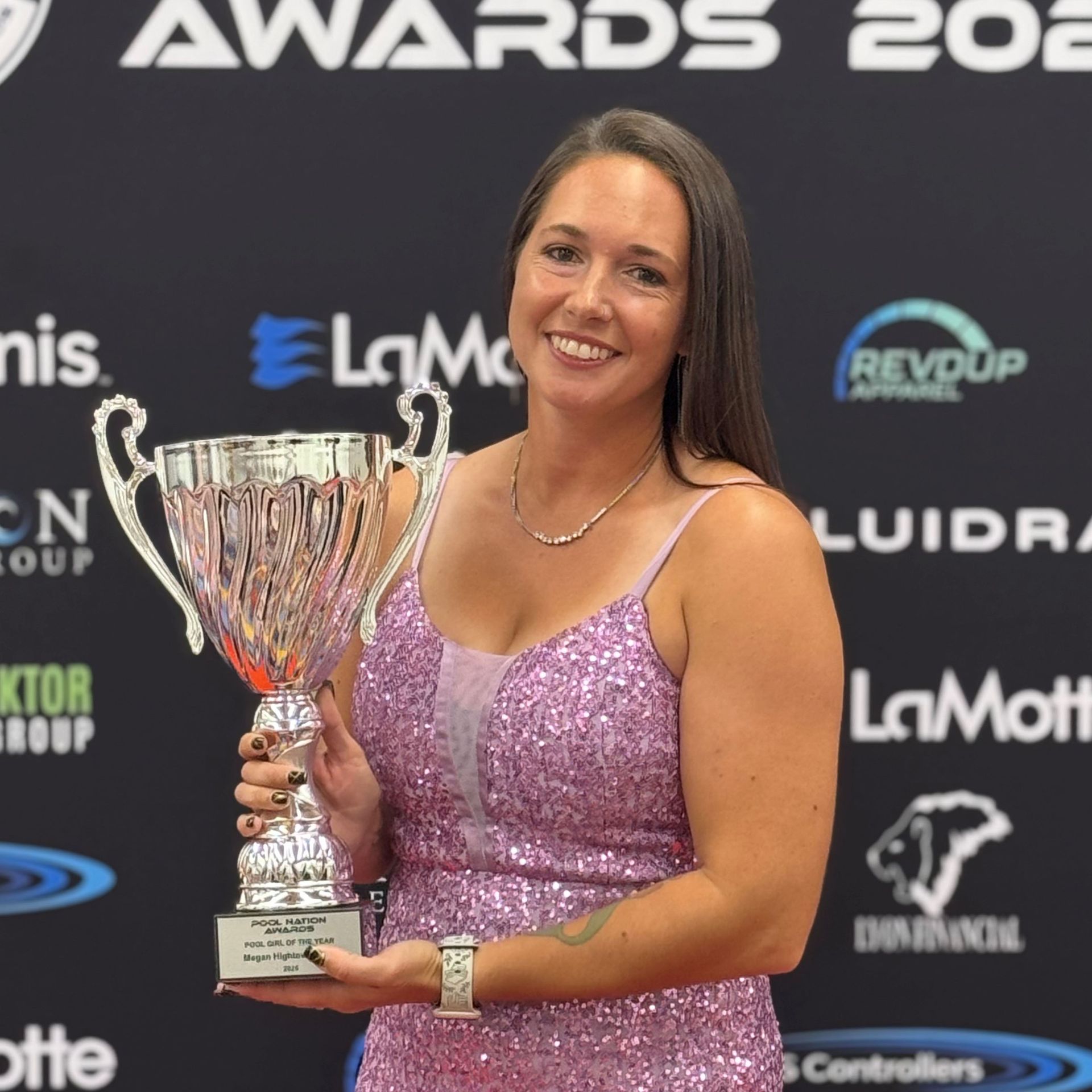Woman in sparkly dress holds a trophy at an awards event.
