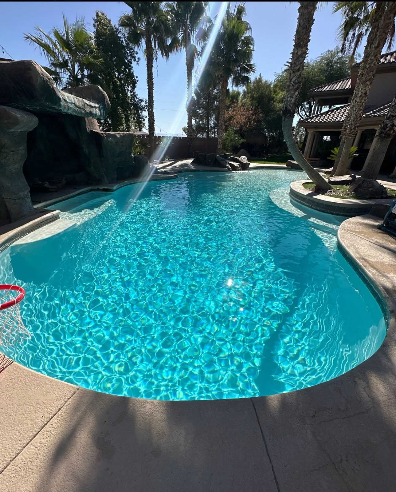 A large swimming pool surrounded by palm trees on a sunny day