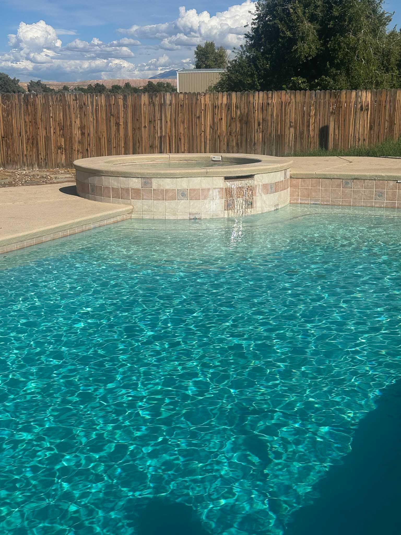 A large swimming pool with a hot tub in the middle of it.