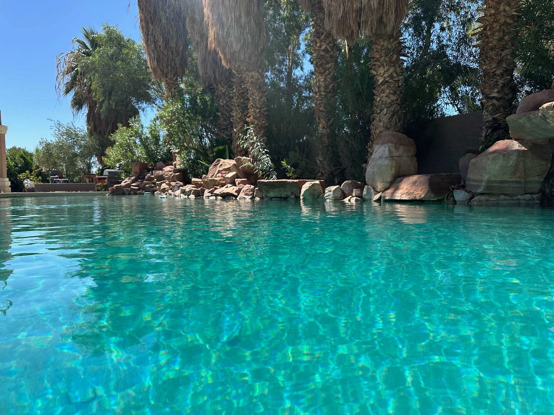 A large swimming pool surrounded by rocks and trees on a sunny day.