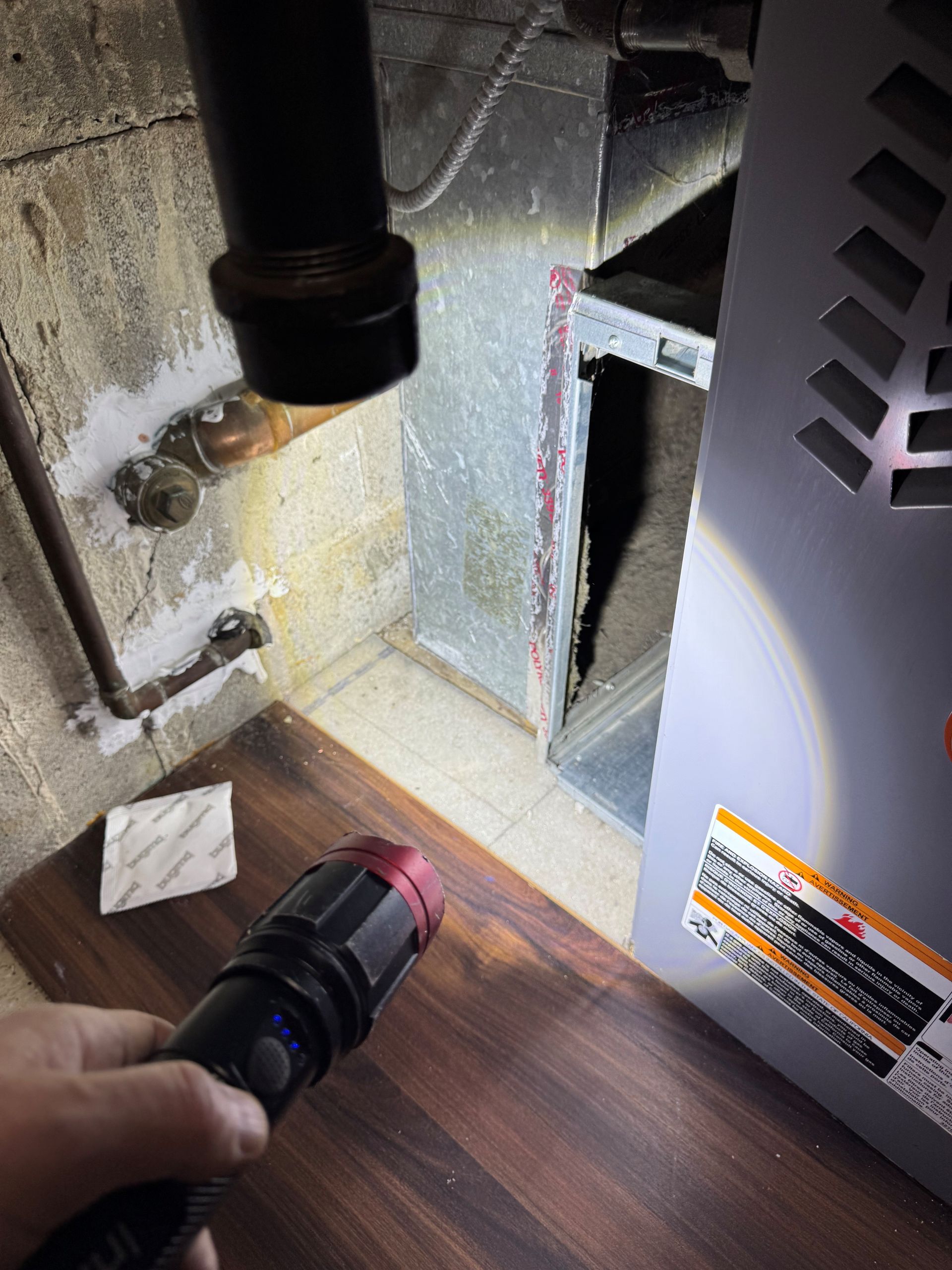 Person in protective suit and mask inspecting ceiling in a building's interior, possibly for hazards.