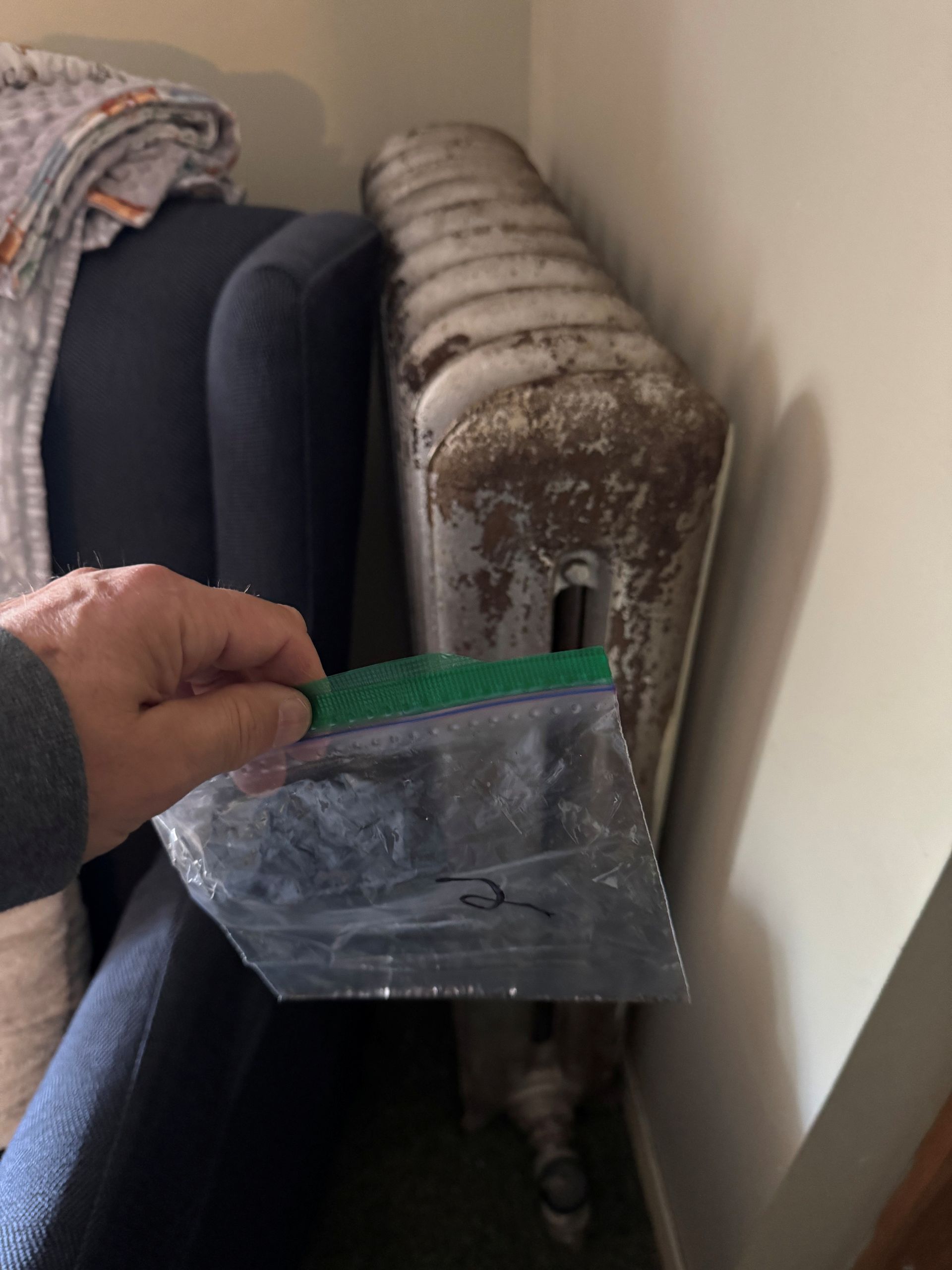 Person in hazmat suit scraping weathered wall.