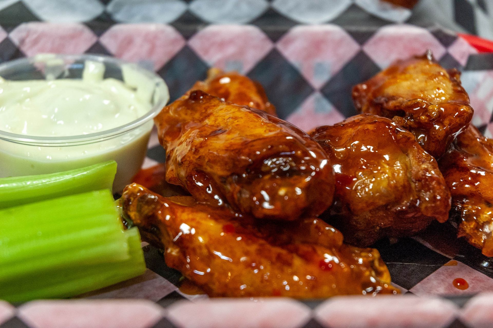 A close up of a plate of chicken wings with celery and ranch dressing.