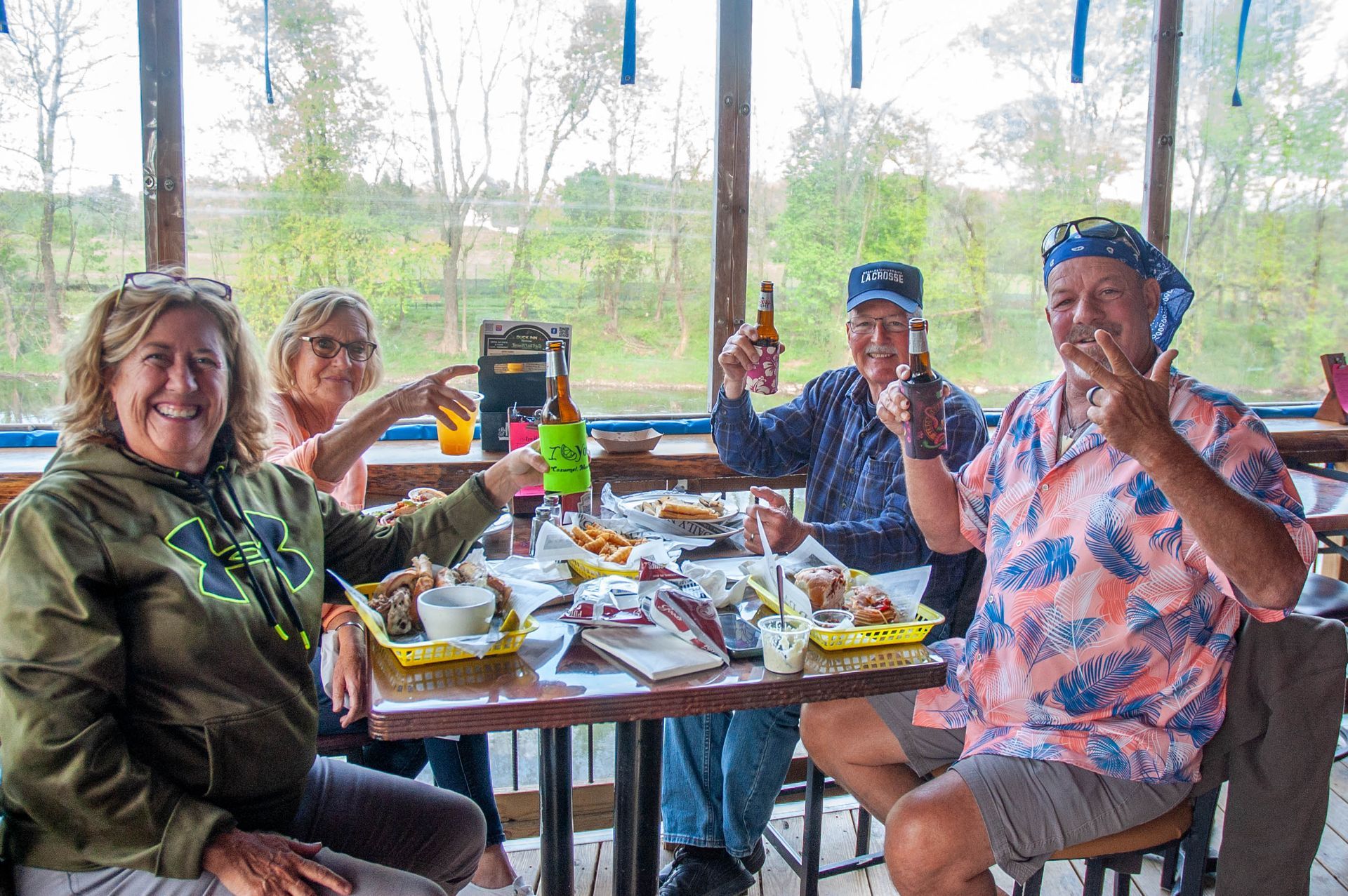 A group of people are sitting at a table in a restaurant toasting with beer.