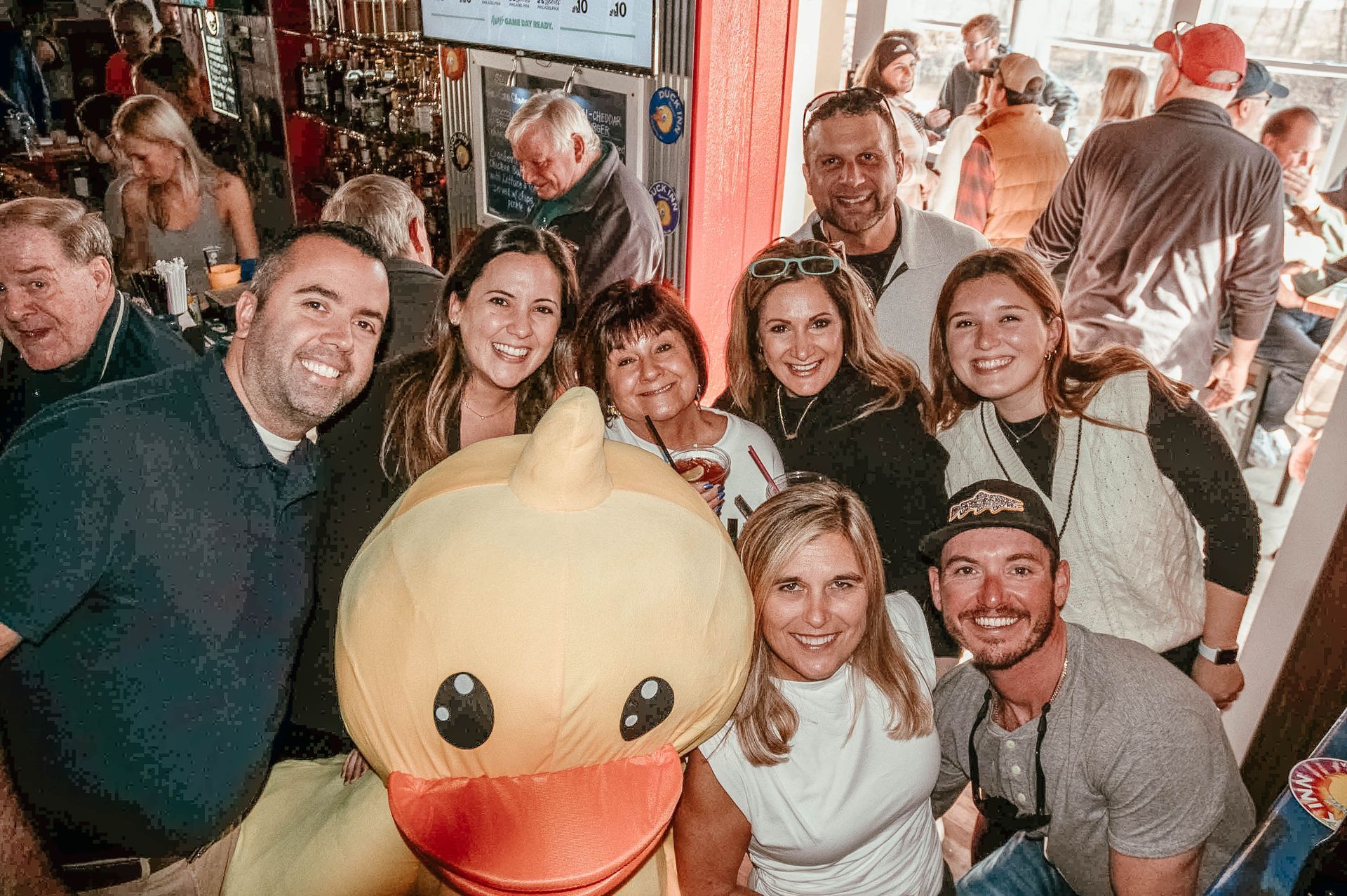 A group of people are posing for a picture with a stuffed duck.