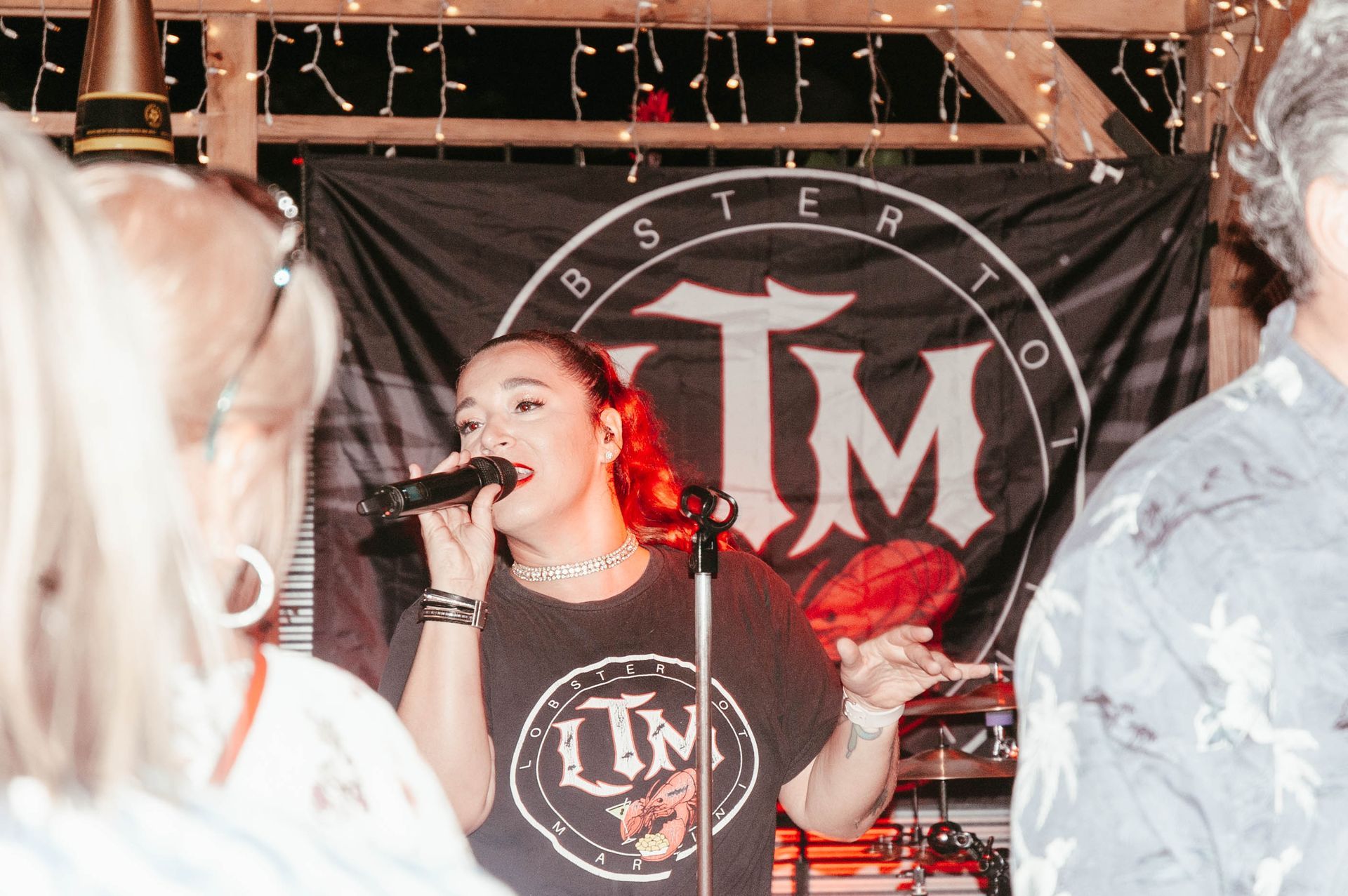 A woman is singing into a microphone in front of a banner that says tm.