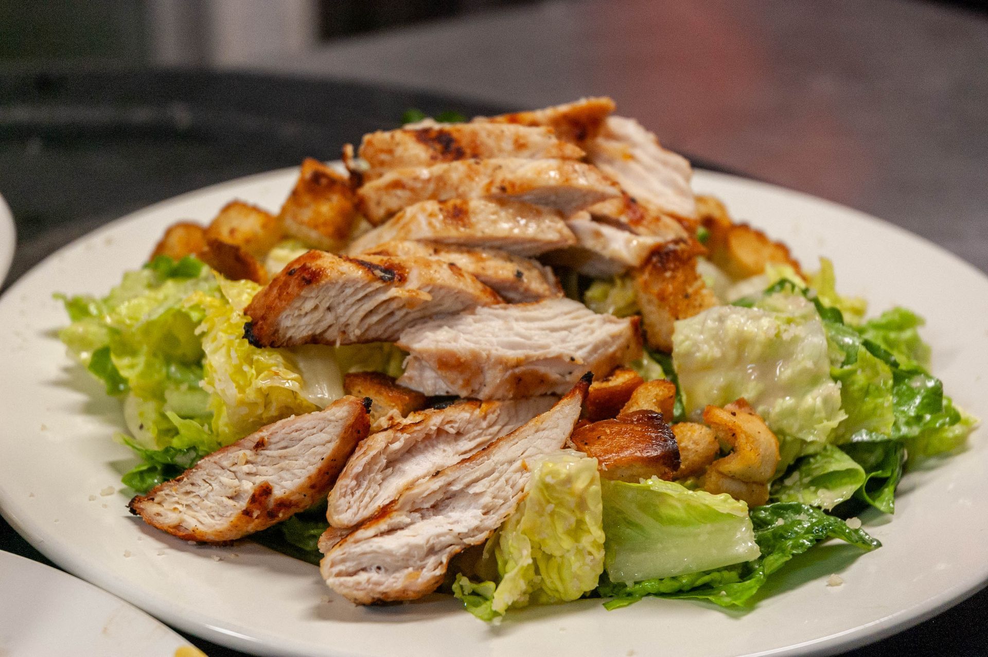 A close up of a plate of food with chicken and lettuce on a table.