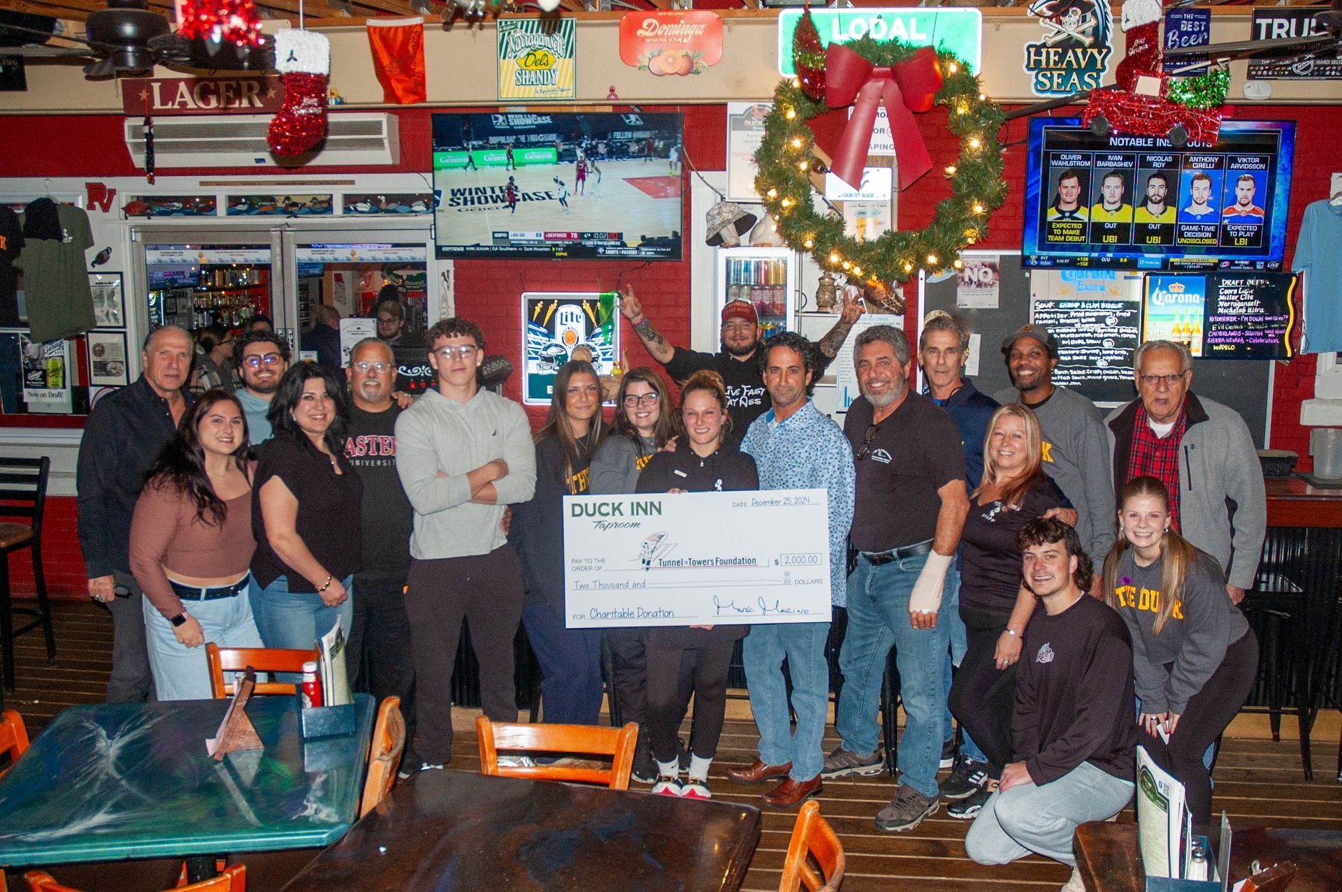 A group of people standing in a restaurant holding a large check.