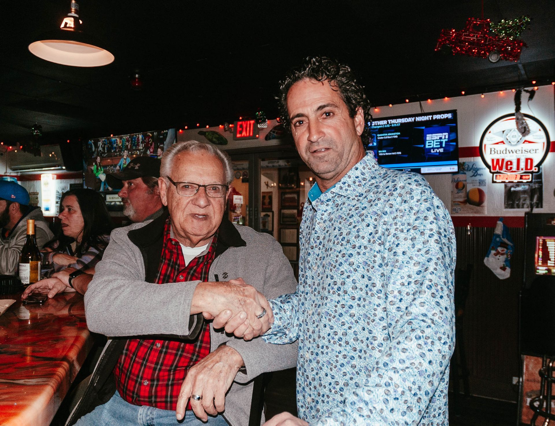 Two men shaking hands in front of a budweiser sign