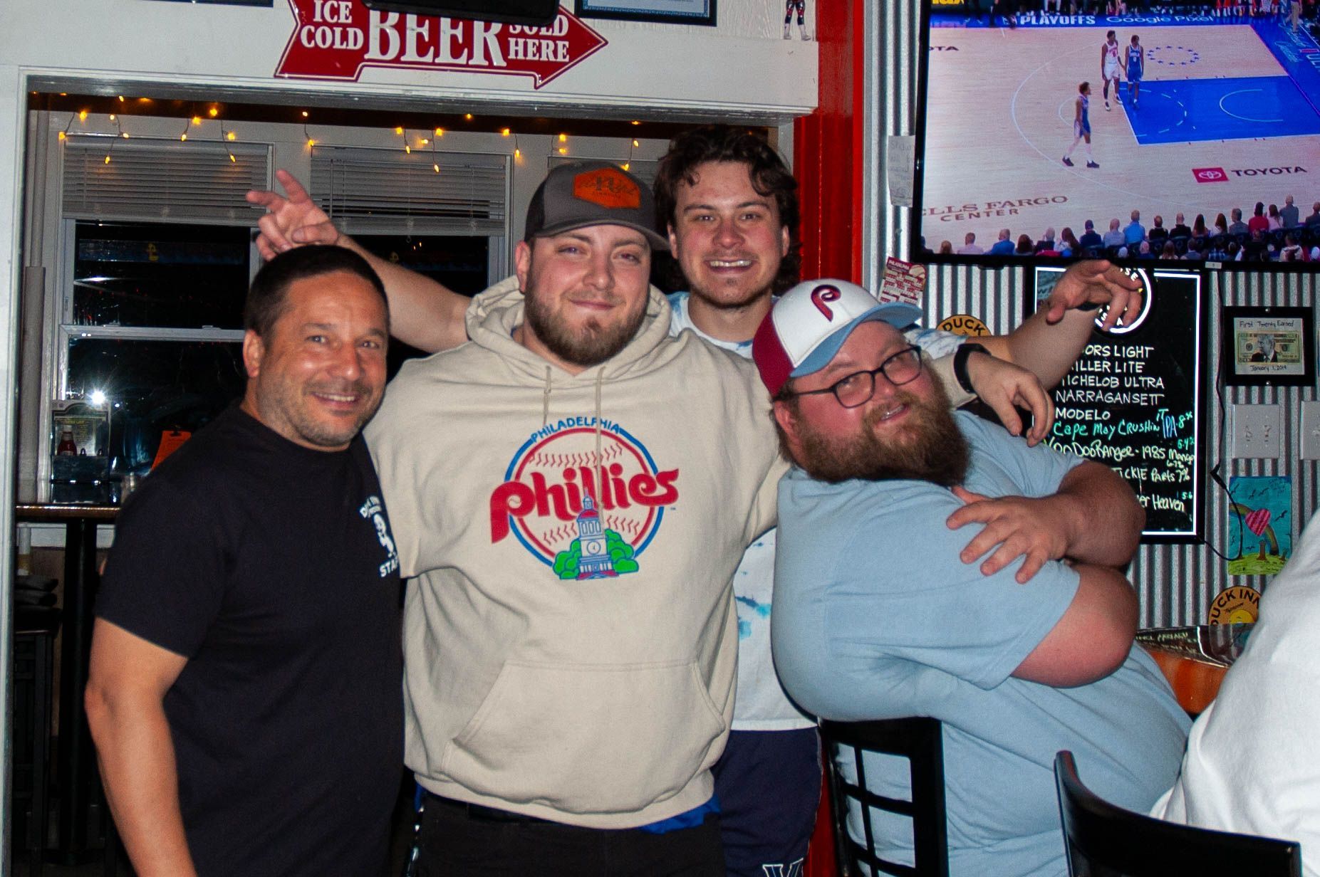 A group of men posing for a picture with one wearing a phillies shirt