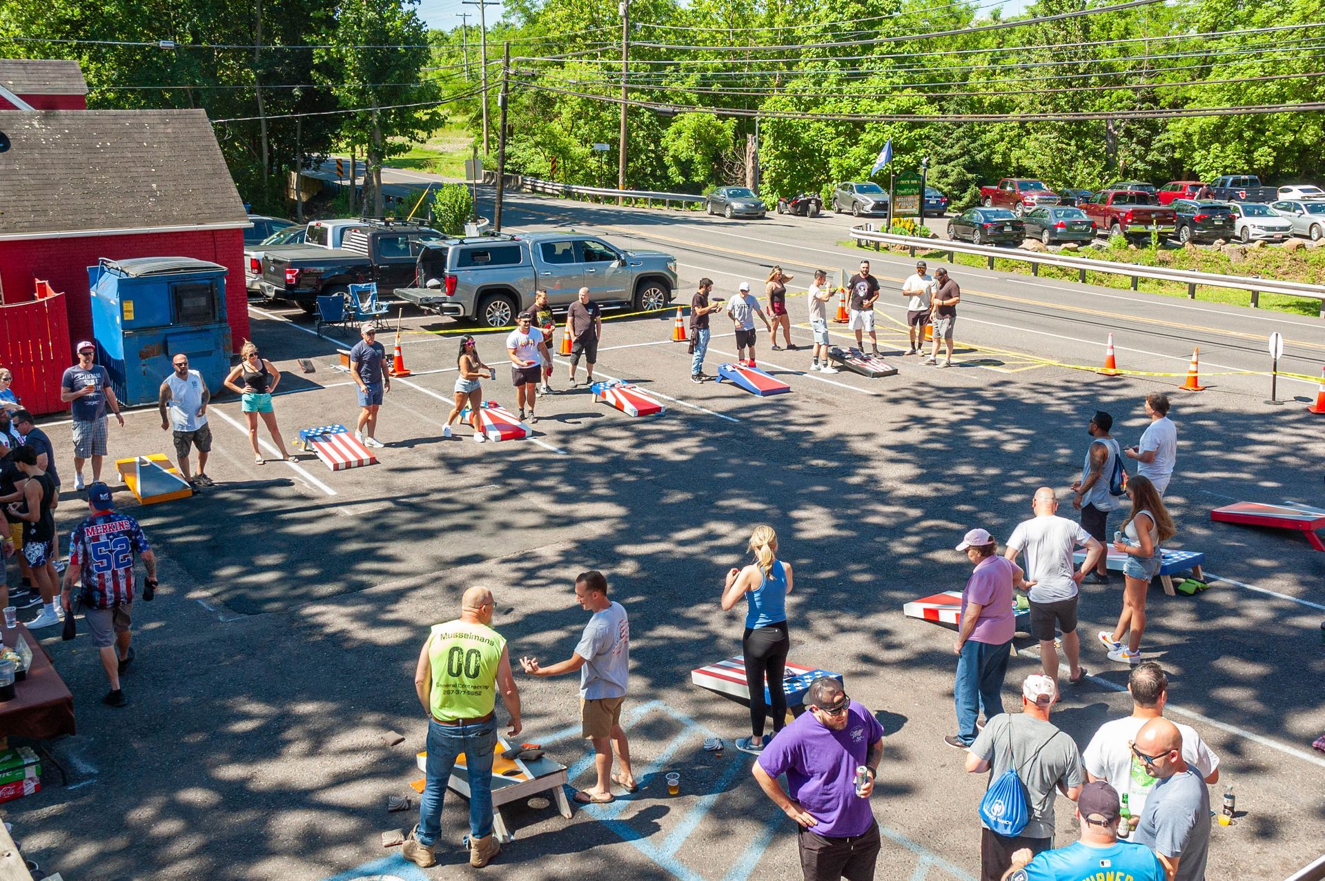 A group of people are playing cornhole in a parking lot.