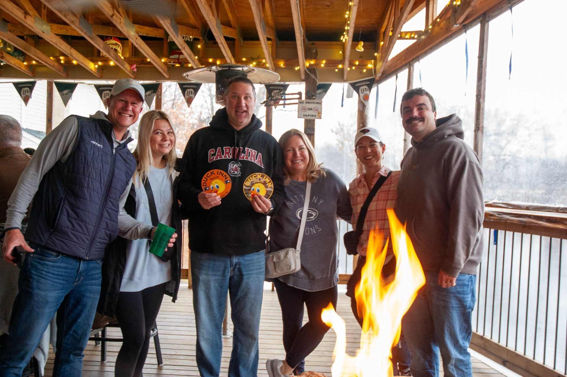 A group of people are posing for a picture in front of a fire pit.