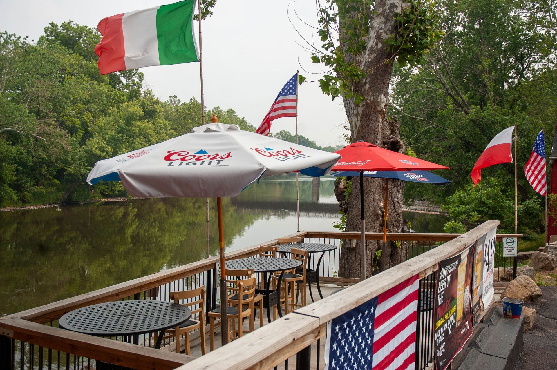 A deck with tables and umbrellas and flags on it