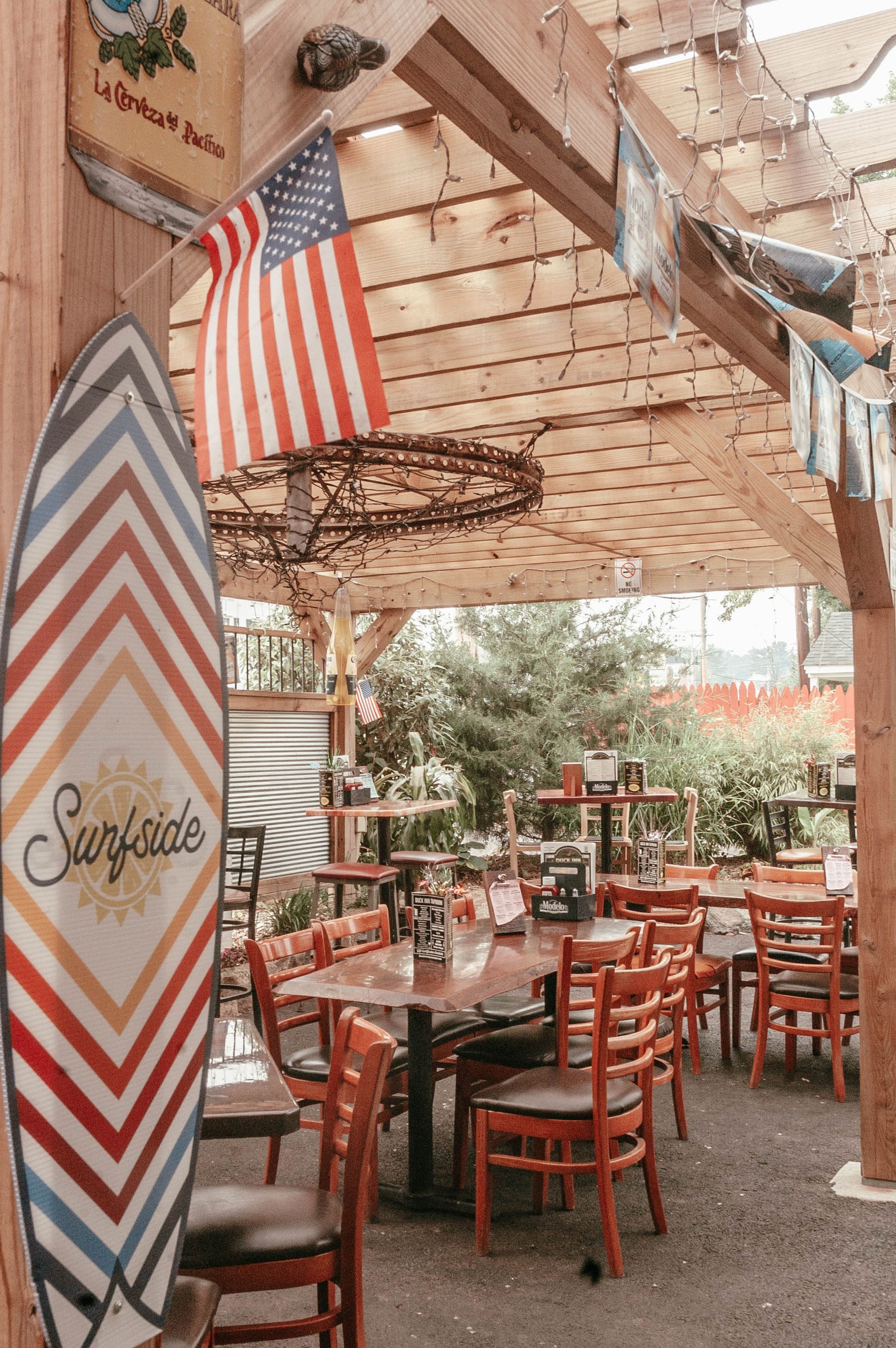 A restaurant with tables and chairs and a surfboard on the wall.