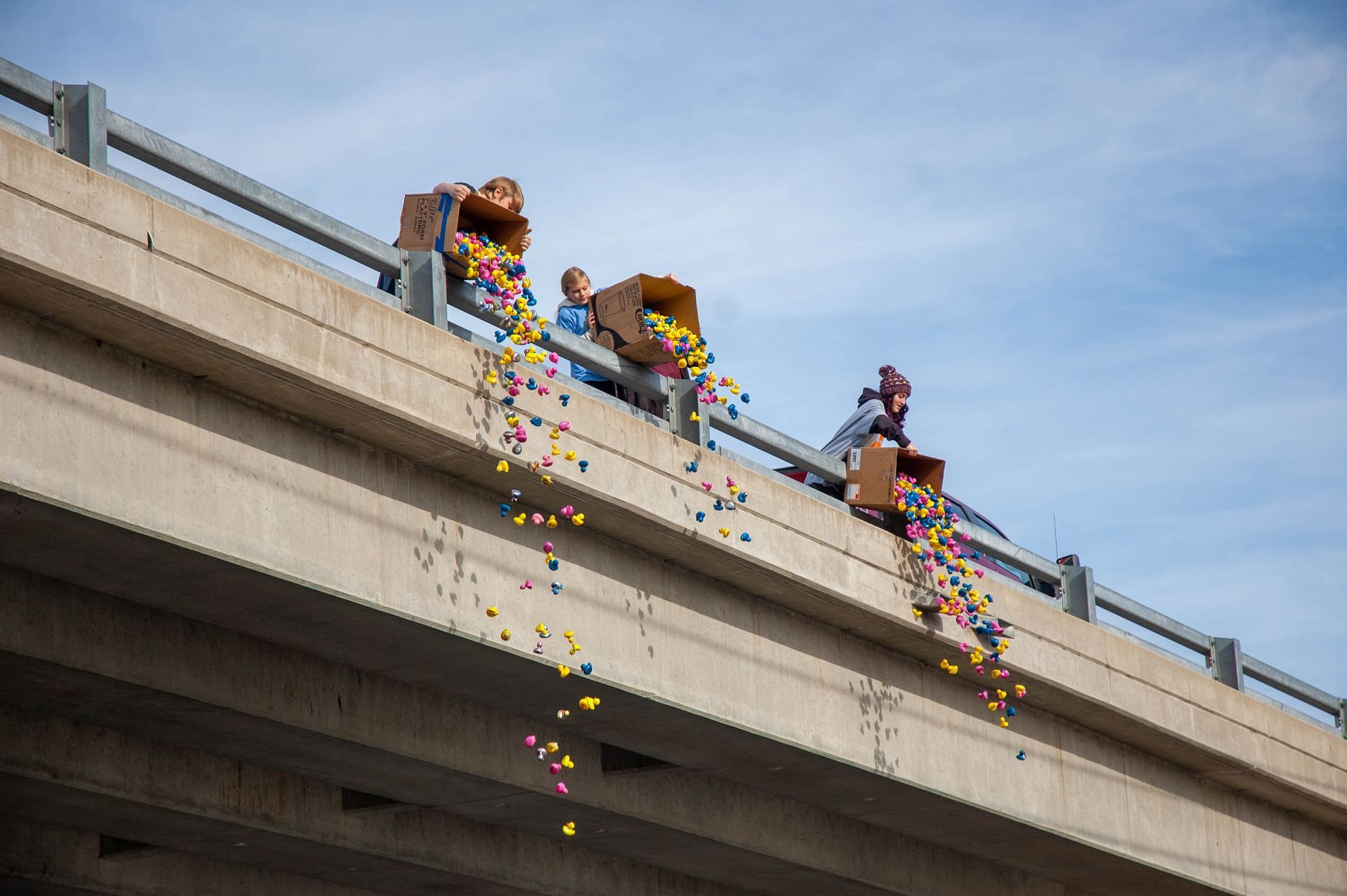 People are throwing balloons from the side of a bridge.