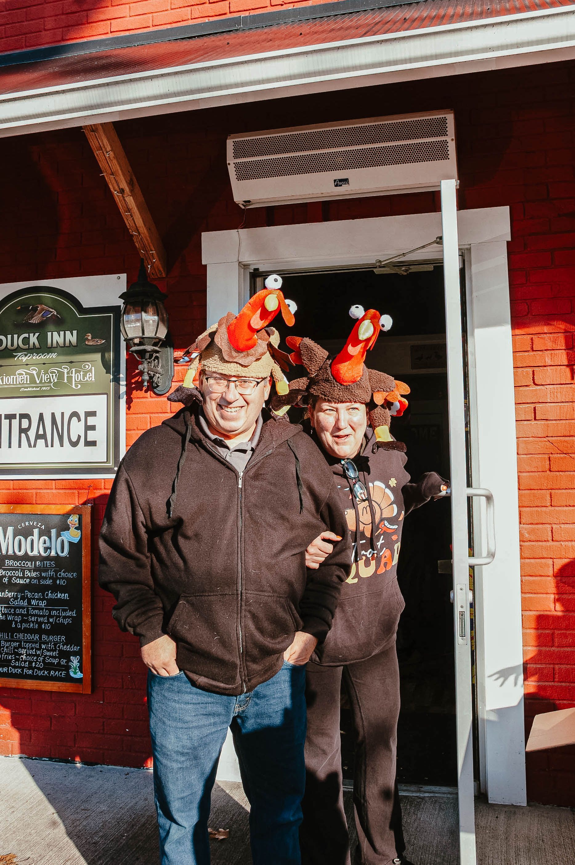 A man and a woman are posing for a picture in front of a red building.