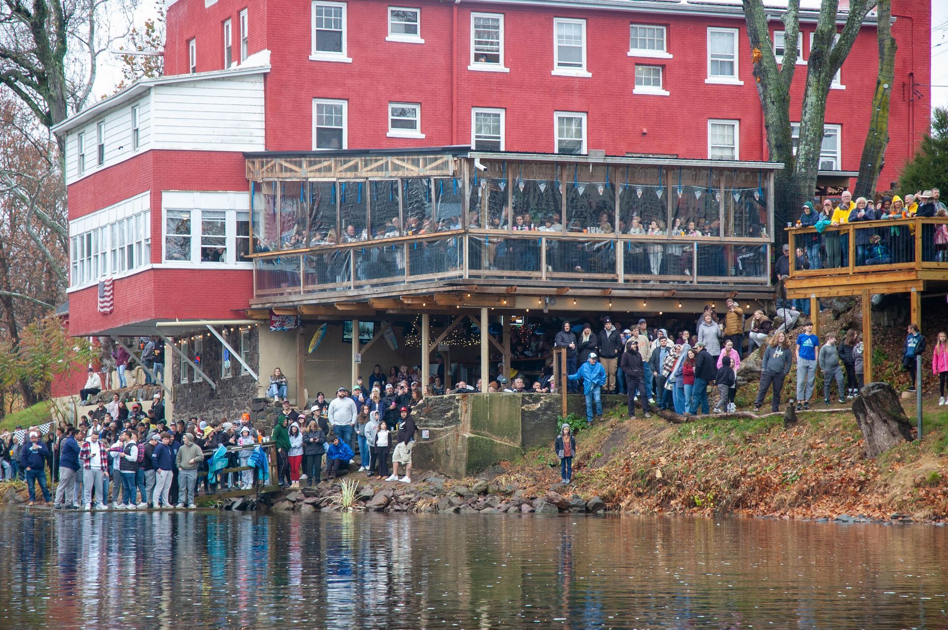 A large group of people are standing in front of a large red building