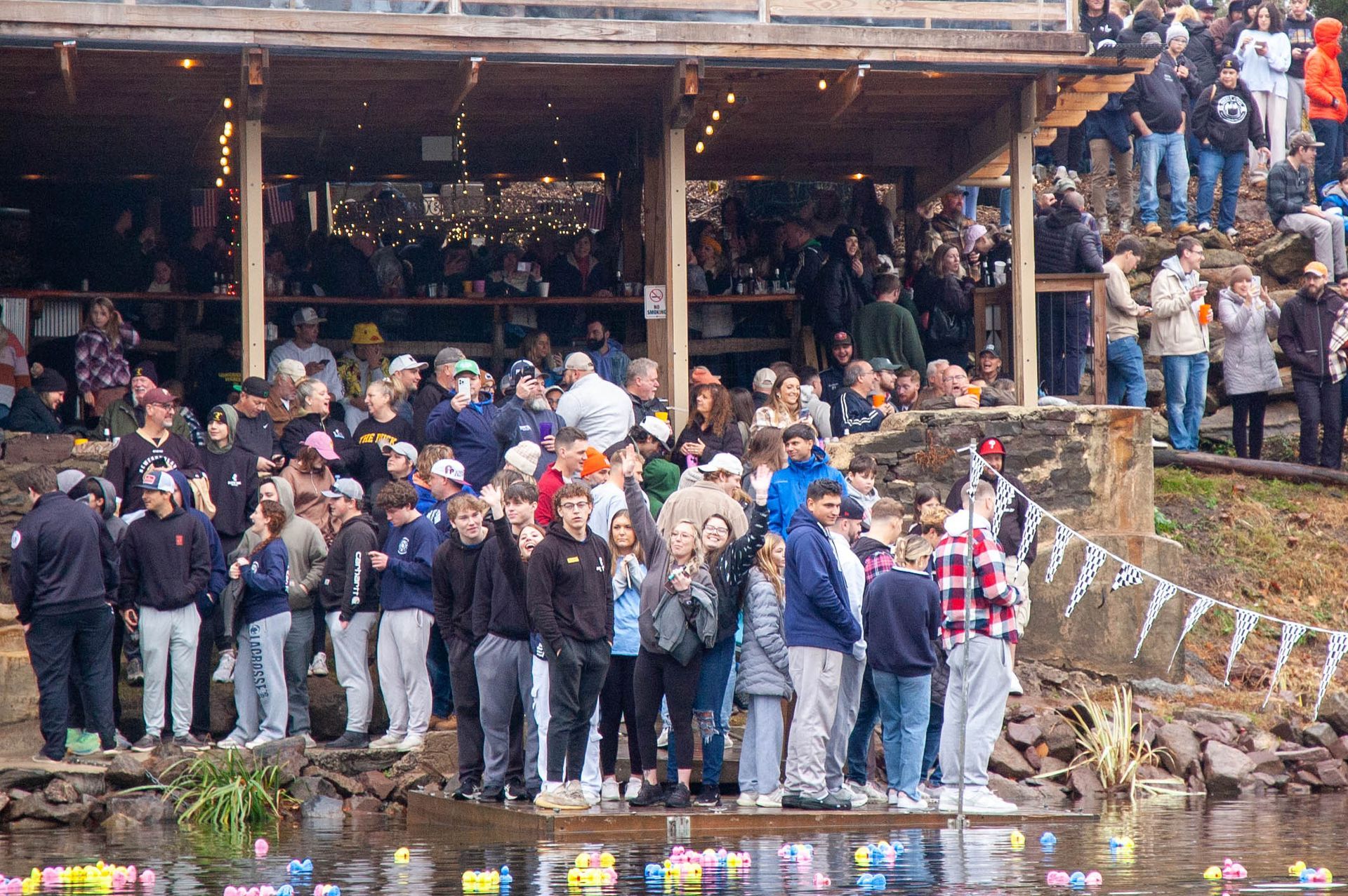 A large group of people are standing next to a body of water.