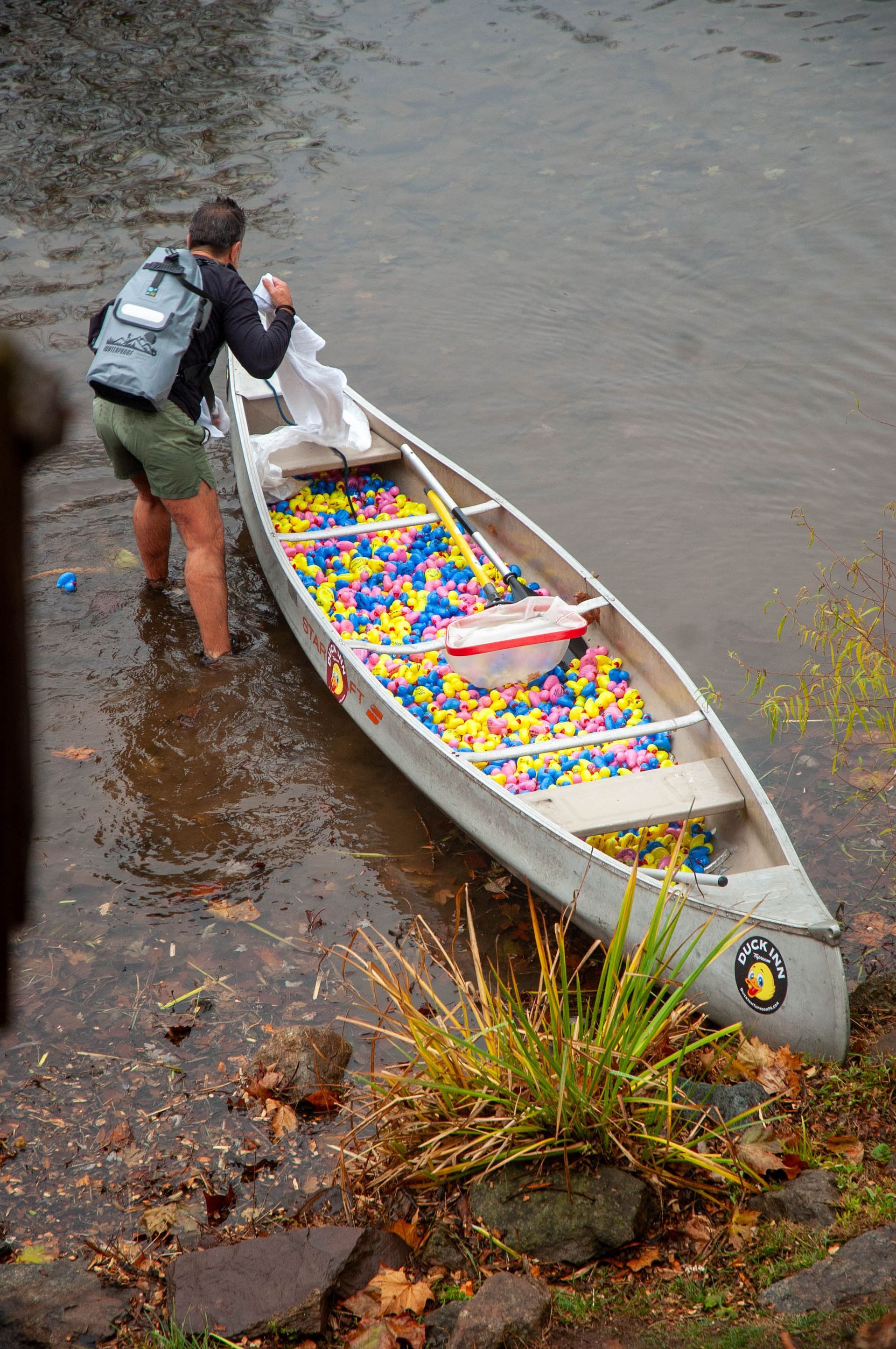 A person is standing next to a canoe filled with lego blocks.