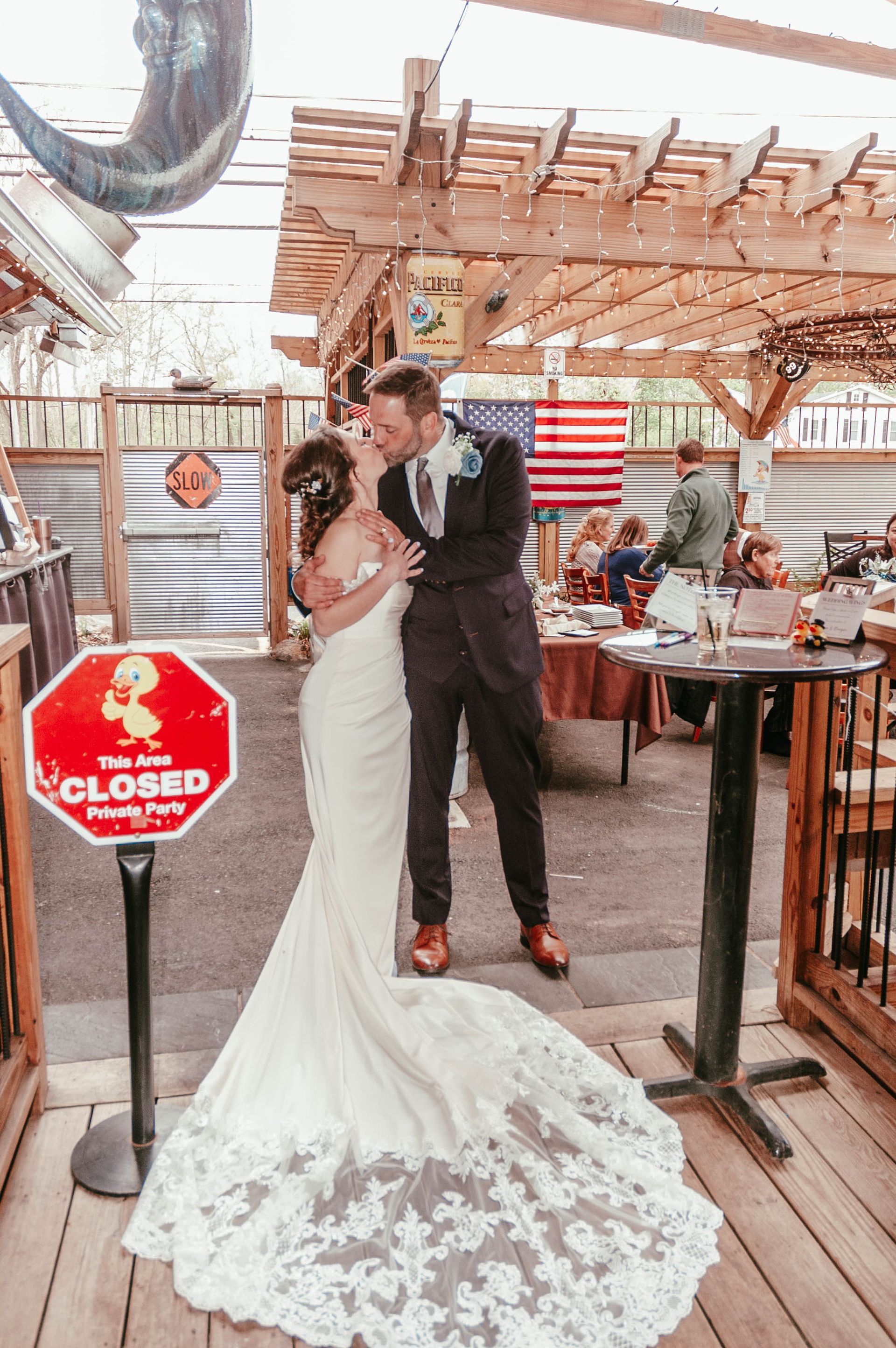 A bride and groom are kissing in front of a stop sign.