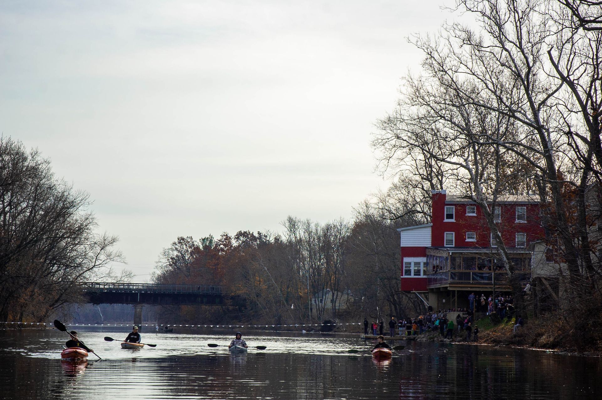 A group of people are rowing kayaks down a river.