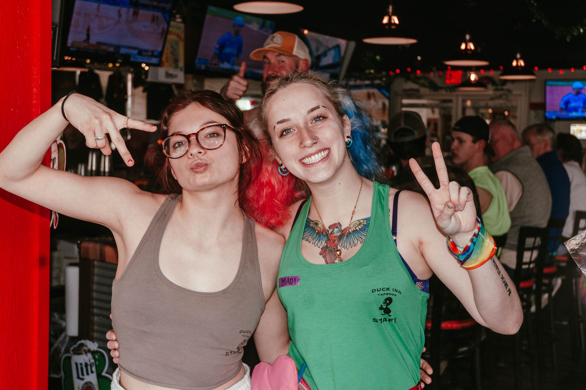 Two young women are posing for a picture in a bar.