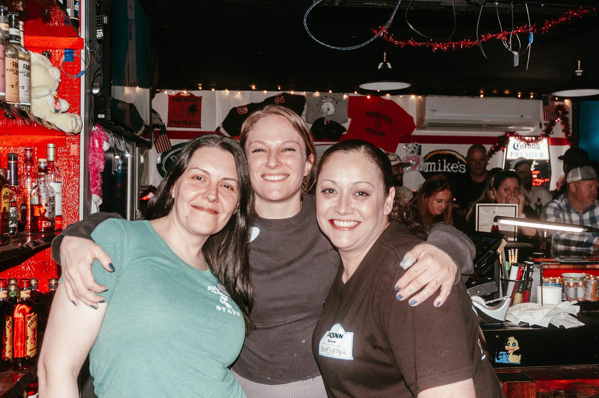 Three women are posing for a picture in a bar.