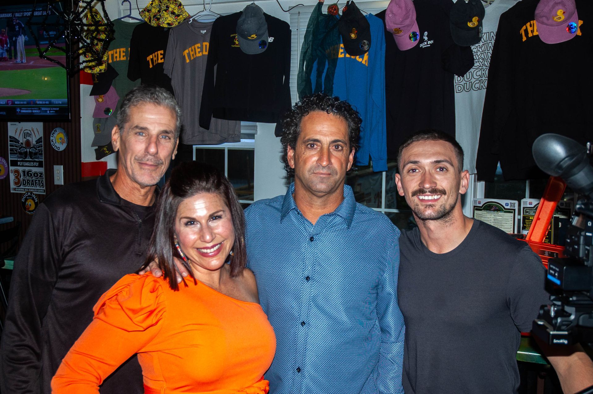 A group of people posing for a picture in front of a wall with shirts on it