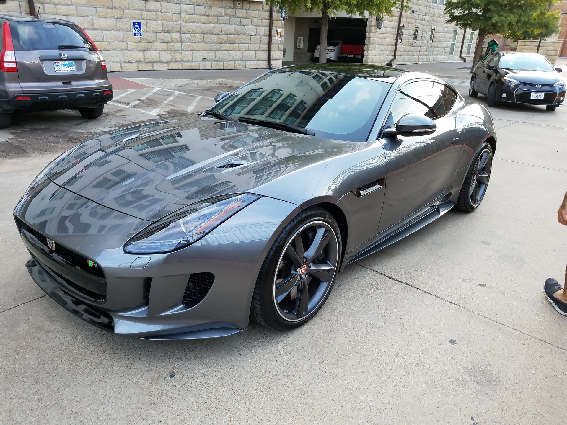 Gray Jaguar sports car parked on a city street.