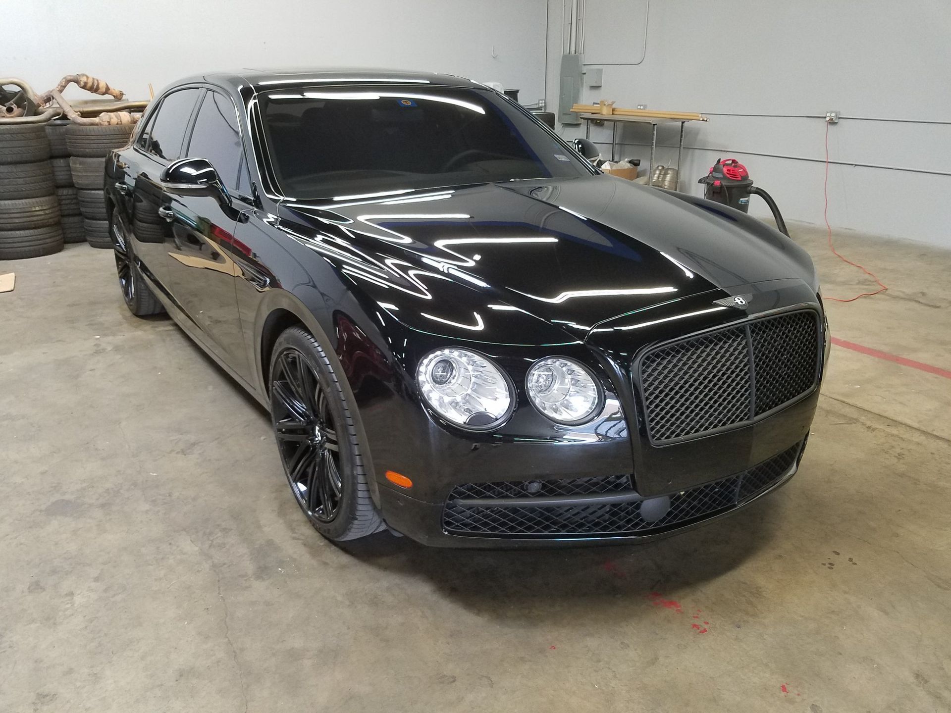 Black Bentley sedan parked in a garage.