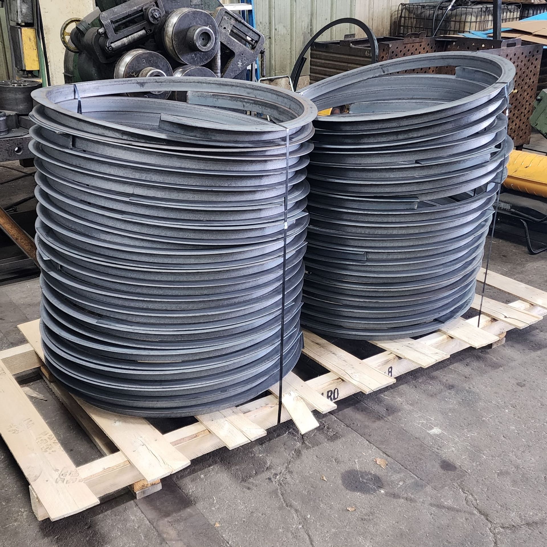 Two stacks of metal pipes are sitting on a wooden pallet.