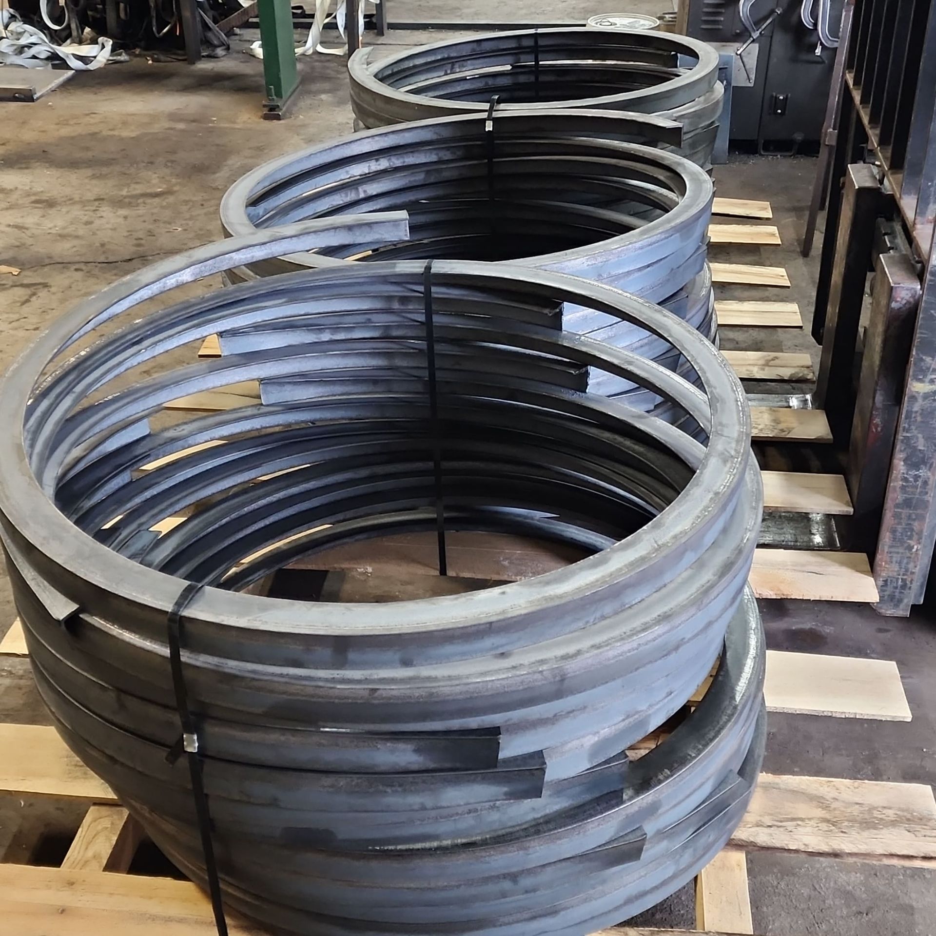 A bunch of metal rings are stacked on top of each other on a wooden pallet.