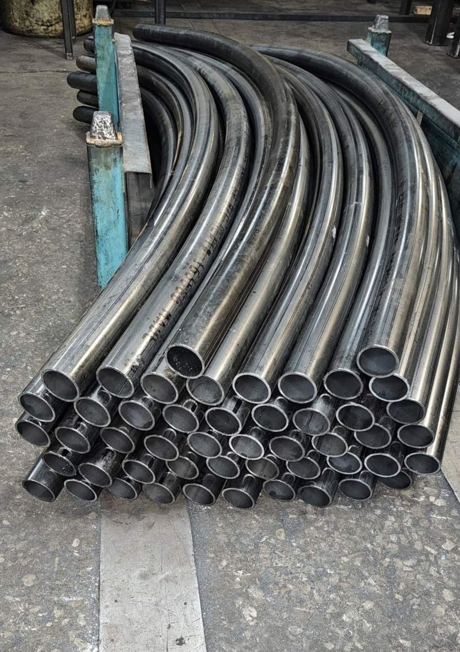 A bunch of metal pipes are stacked on top of each other on the ground.