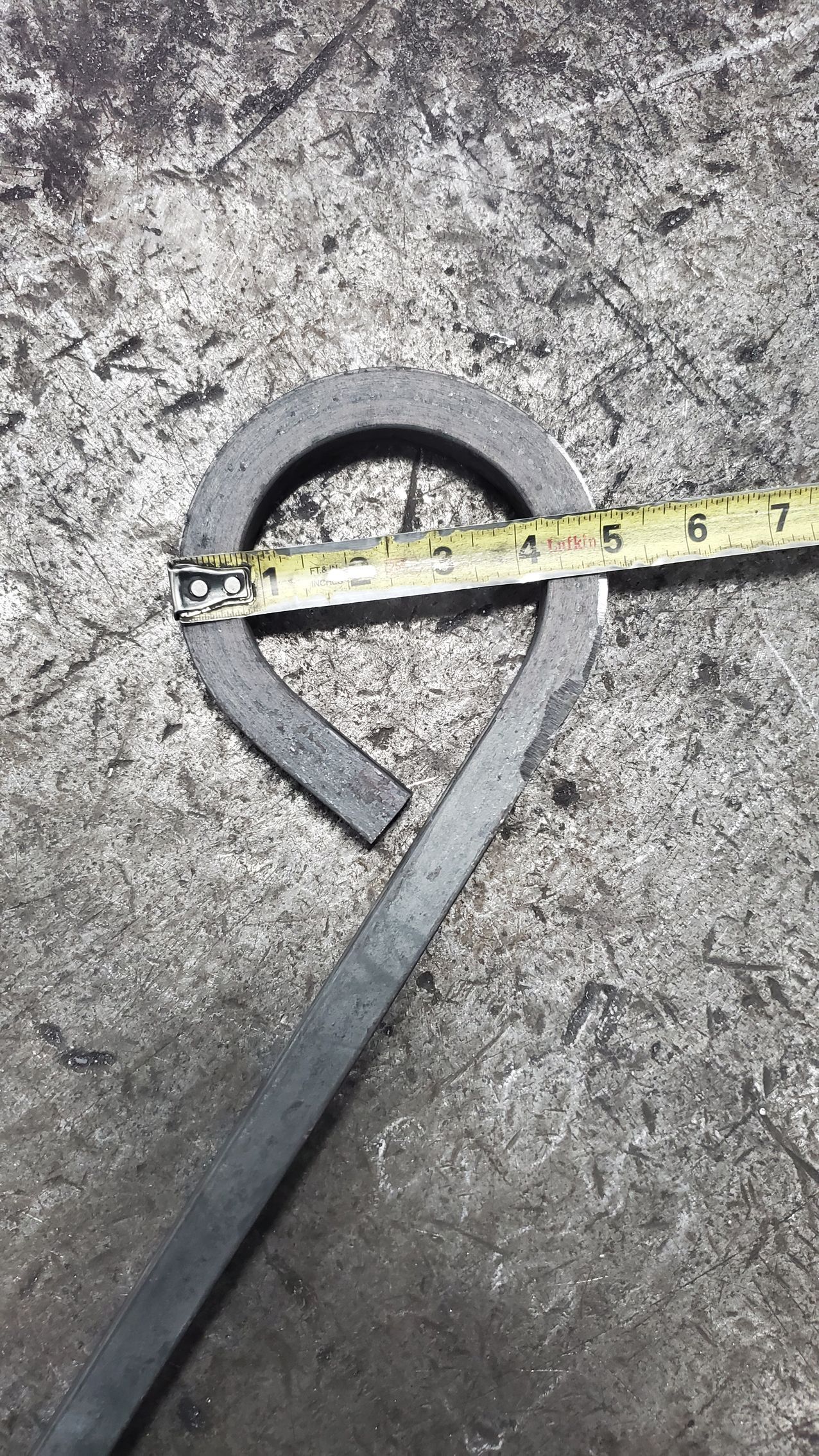 A piece of metal is being measured with a tape measure.