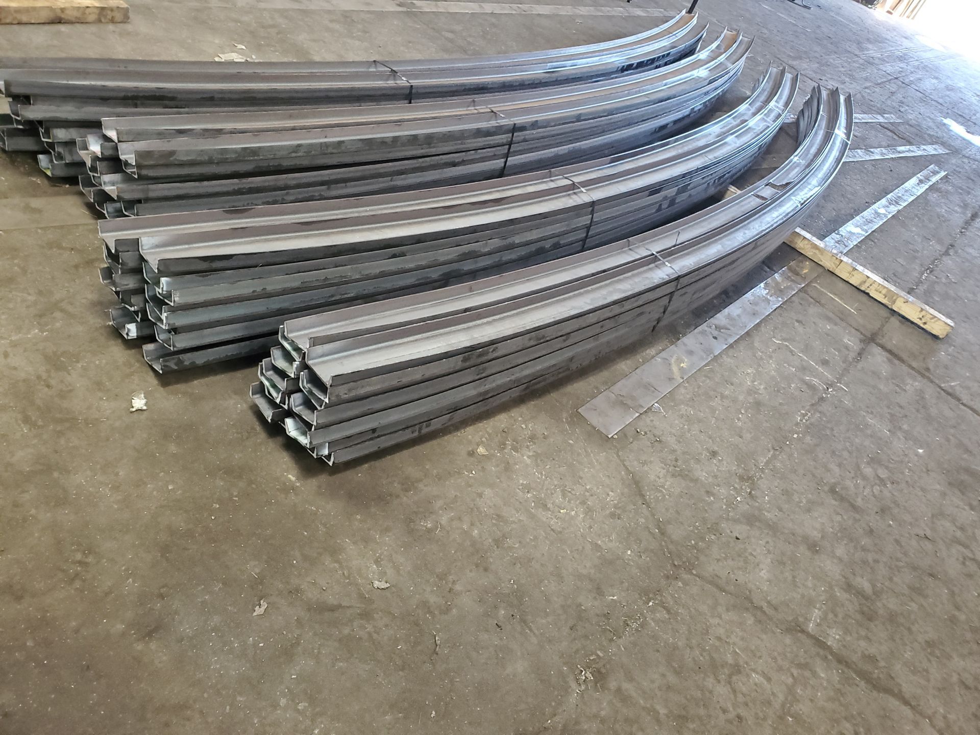 A bunch of metal pipes are stacked on top of each other on a concrete floor.