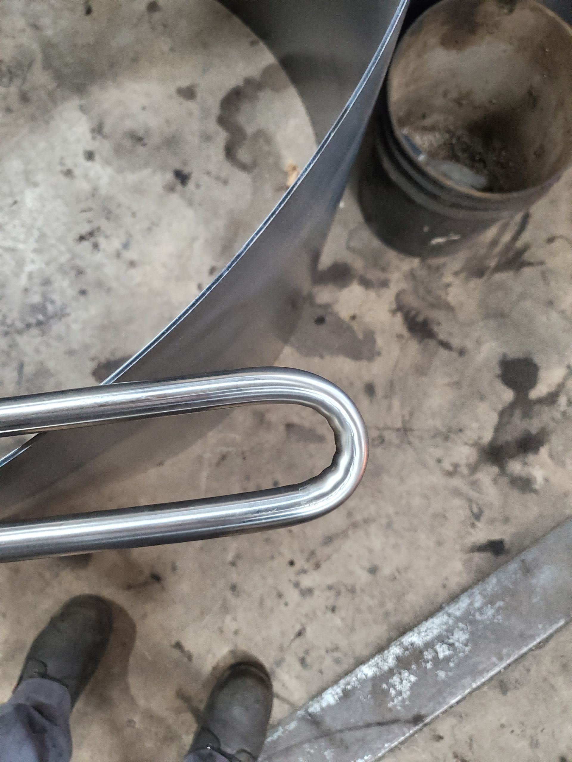 A person is standing next to a metal pipe on the ground.