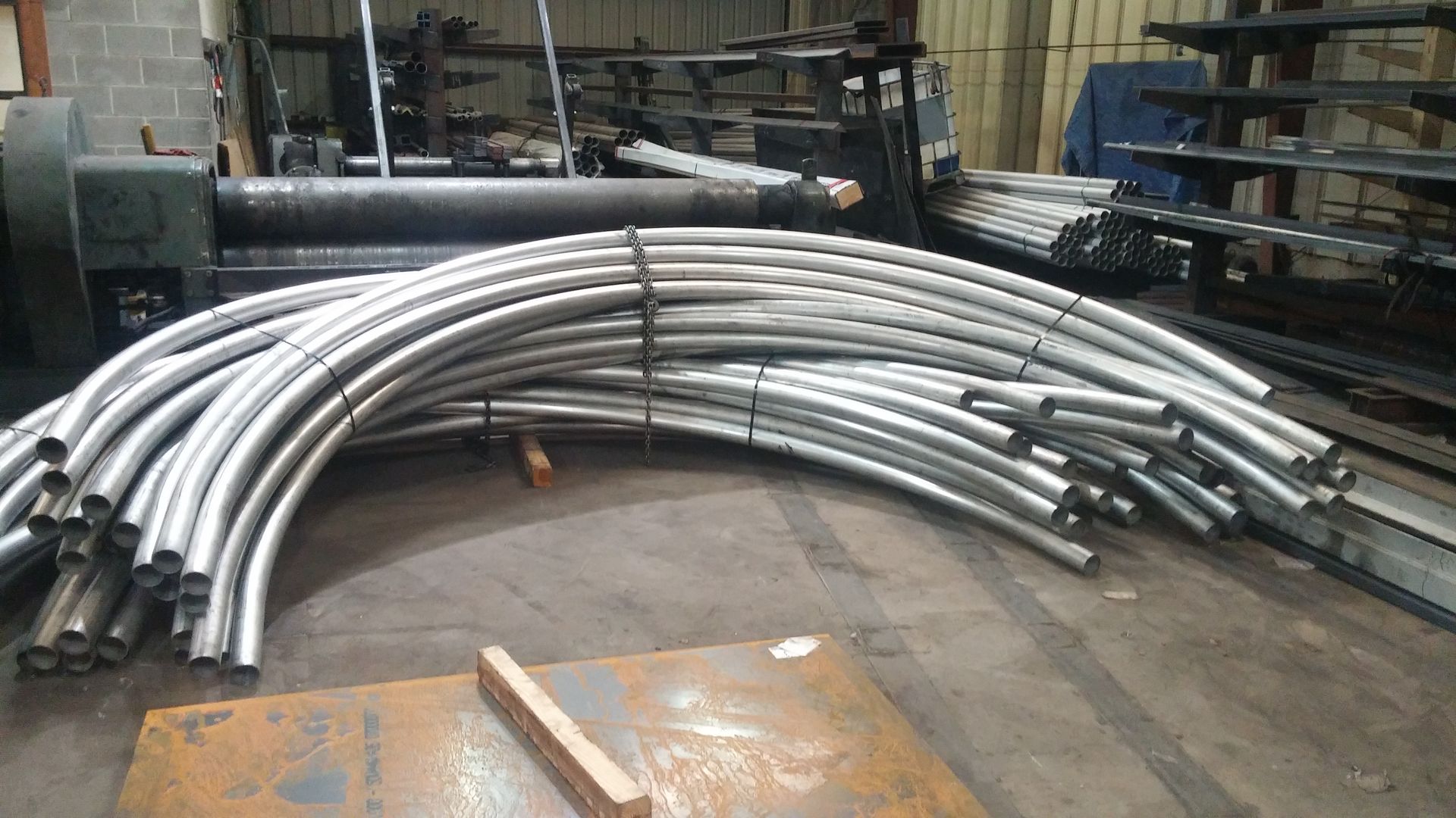 A bunch of metal pipes are stacked on top of each other in a warehouse.
