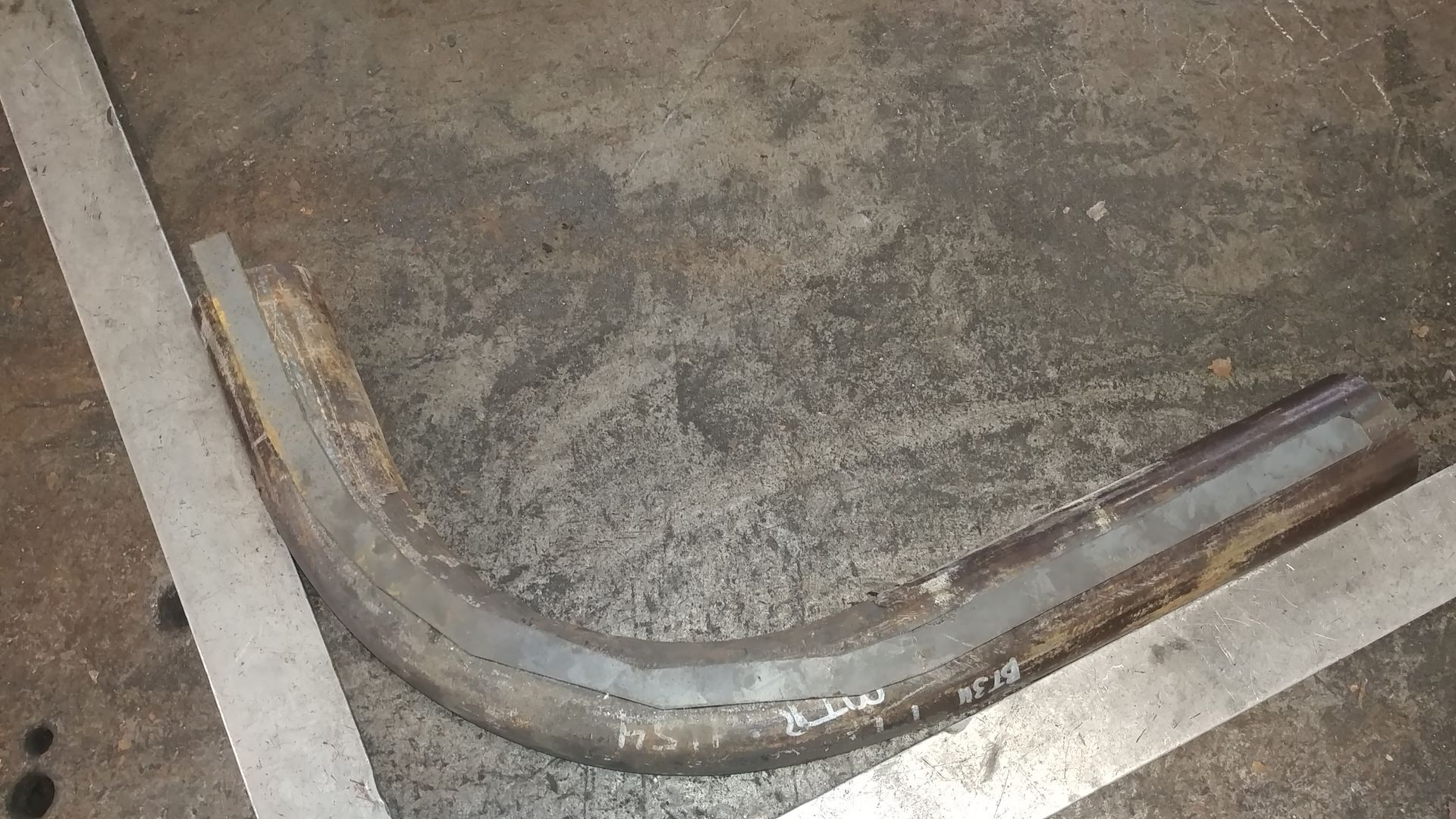 A metal pipe is sitting on the ground next to a white line.