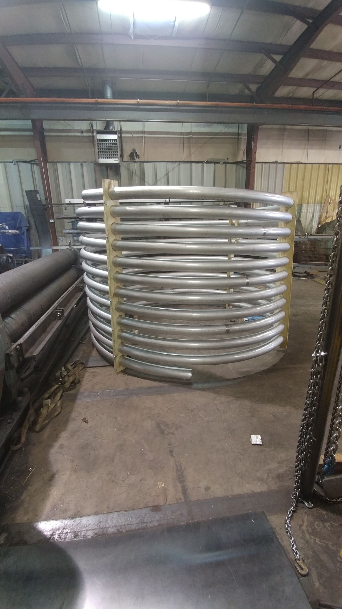 A large metal pipe is sitting on the floor in a factory.