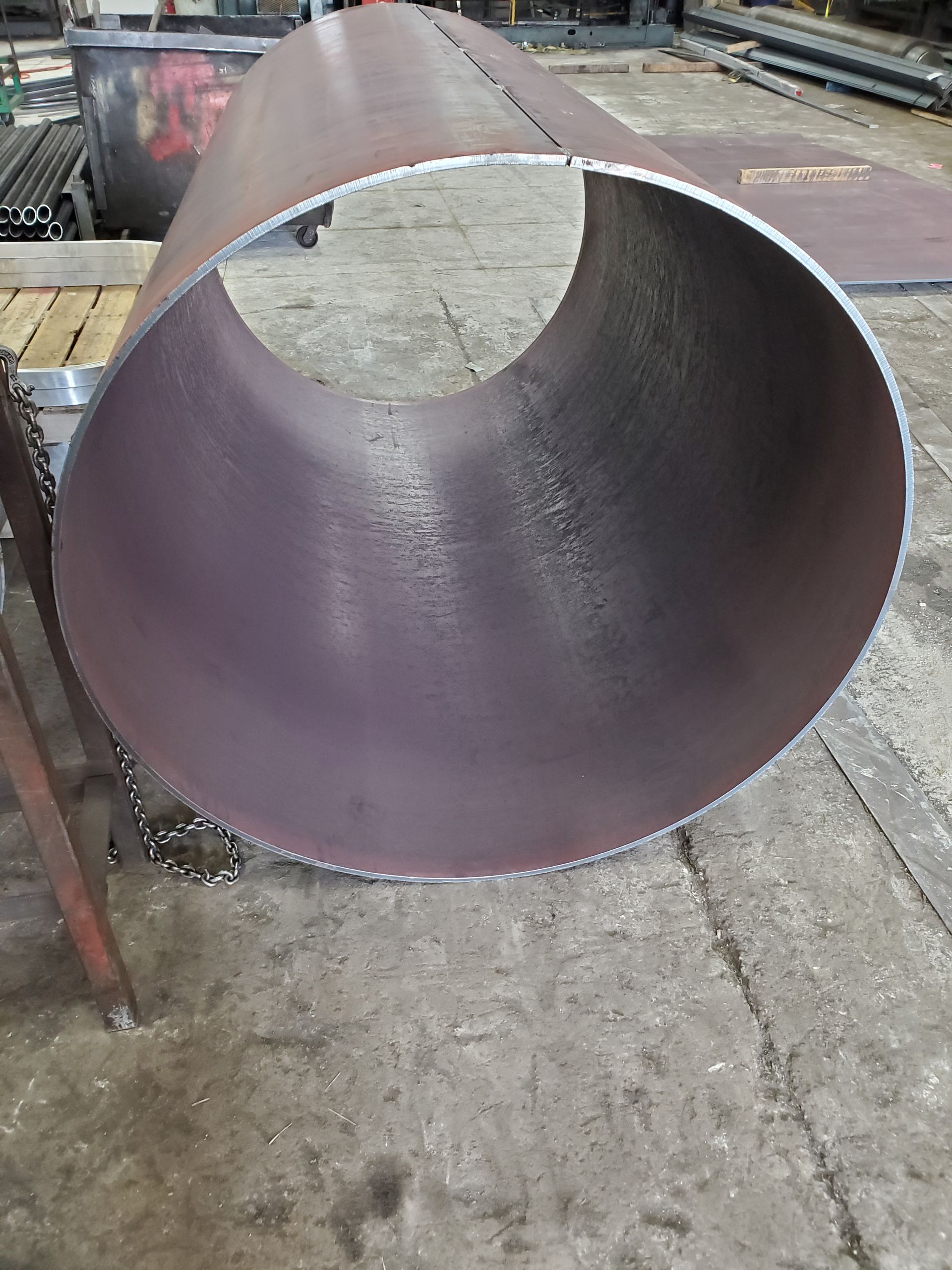 A large metal pipe with a hole in the middle is sitting on the ground.