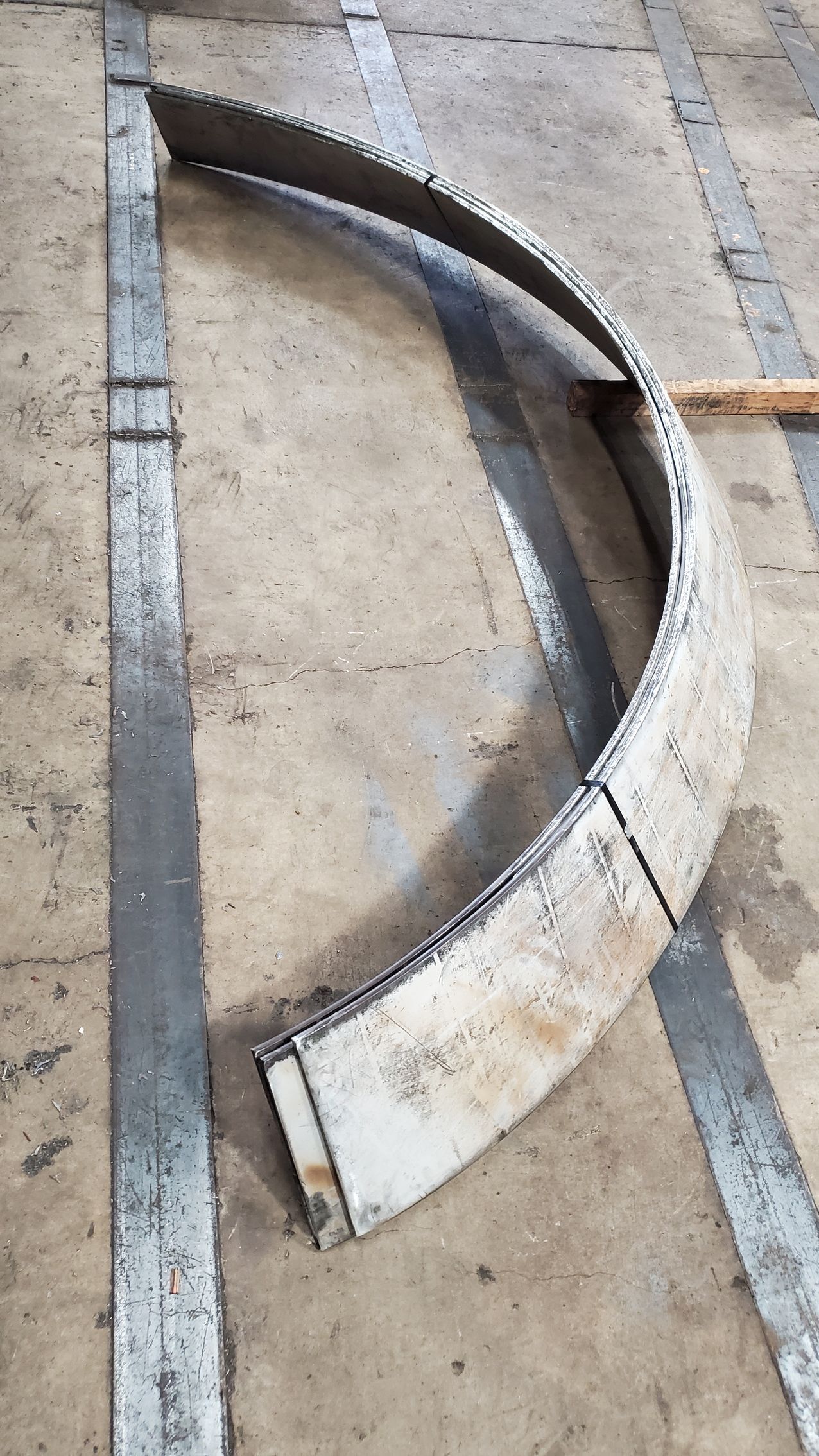 A piece of metal is laying on the ground next to a concrete line.