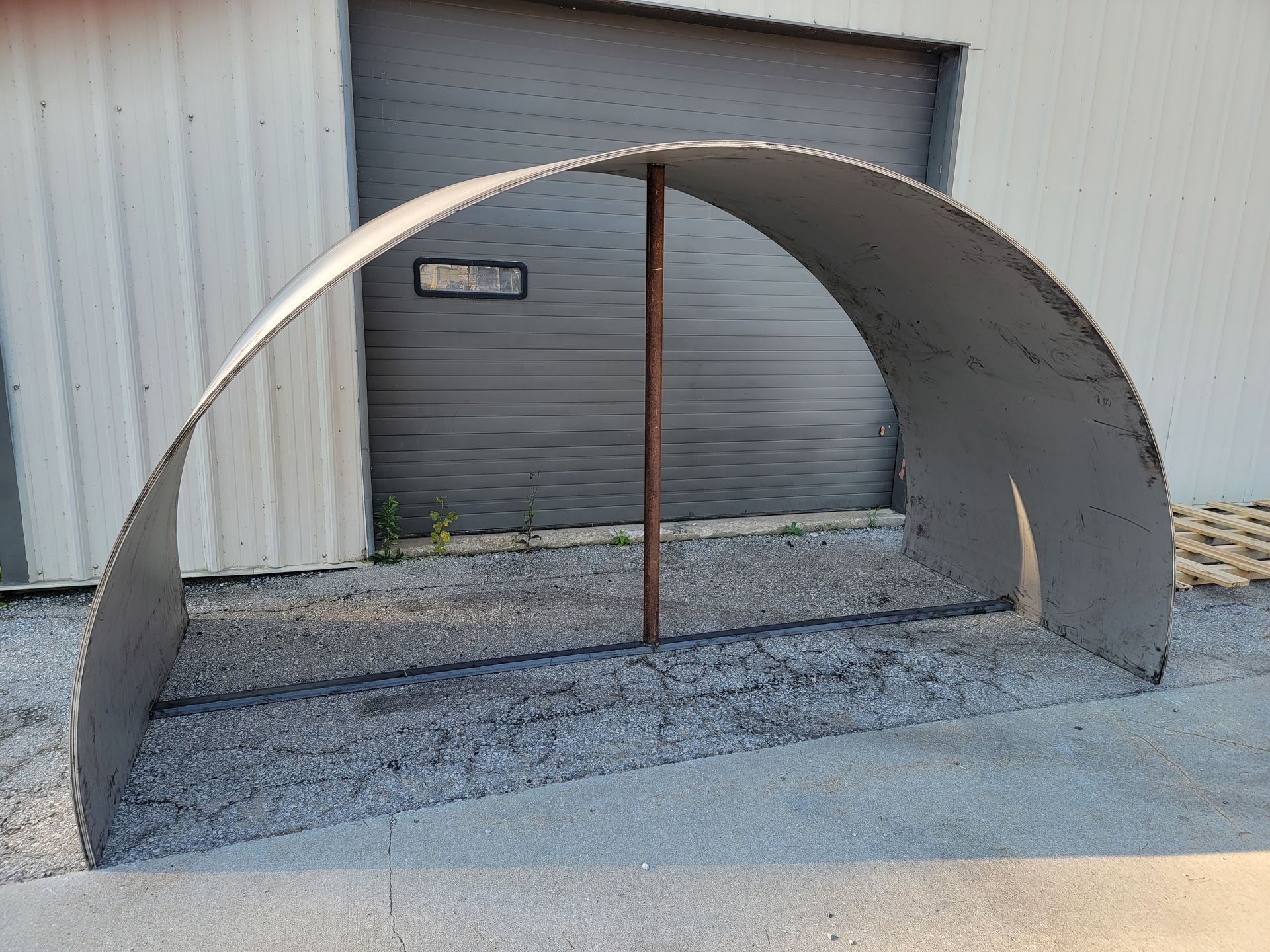 A large metal arch is sitting in front of a garage door.