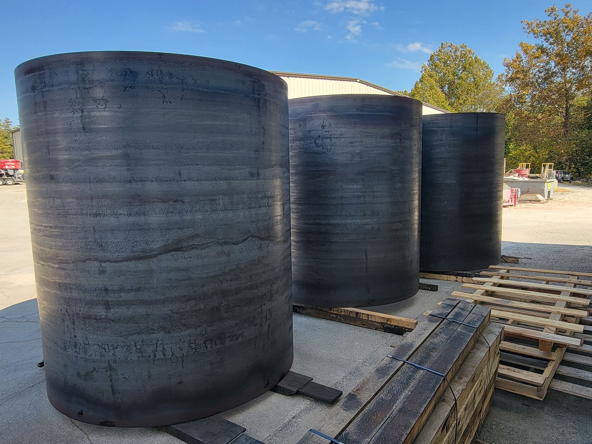 A row of black cylinders sitting on top of wooden pallets