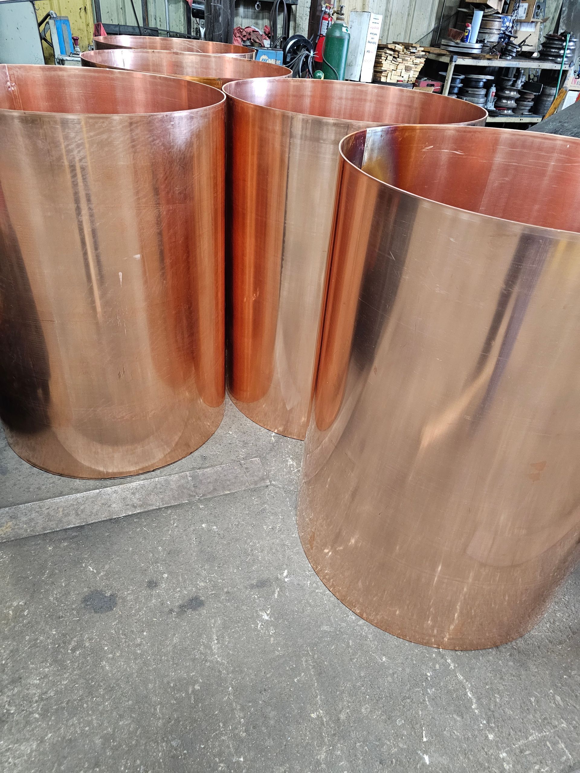 A group of copper pipes sitting on top of a cement floor.