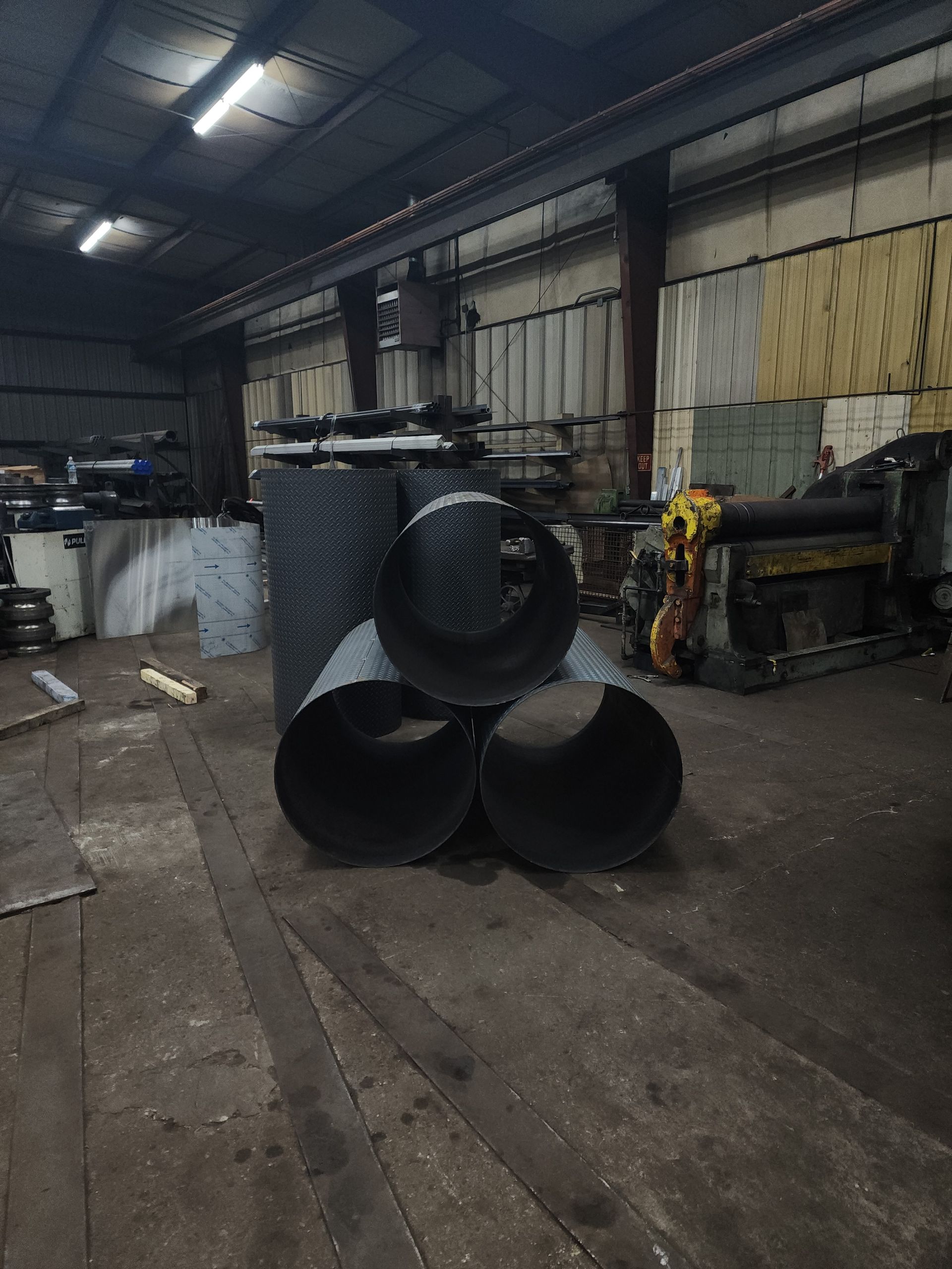 A bunch of metal pipes are stacked on top of each other in a factory.