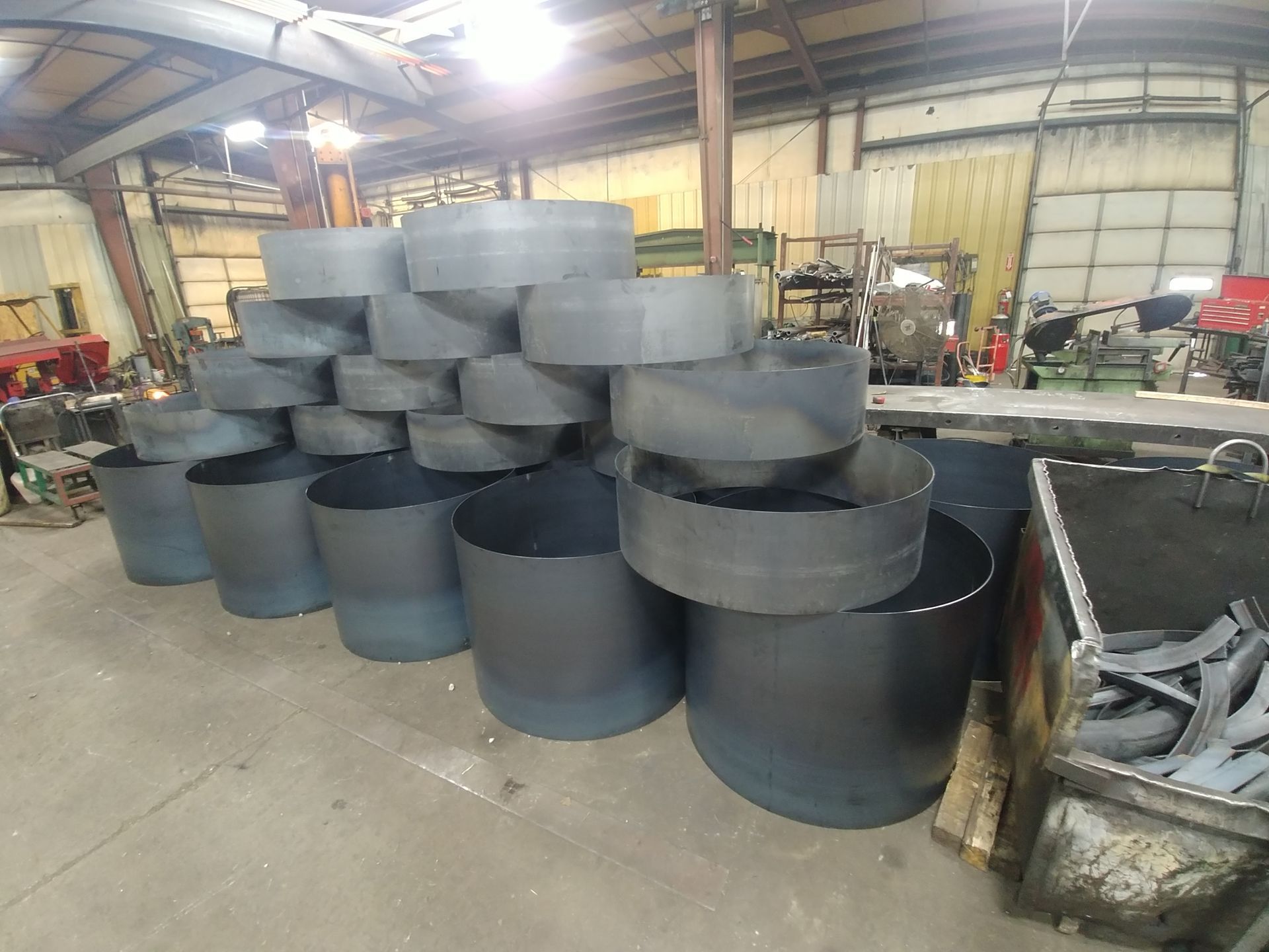 A bunch of metal pipes are stacked on top of each other in a factory.