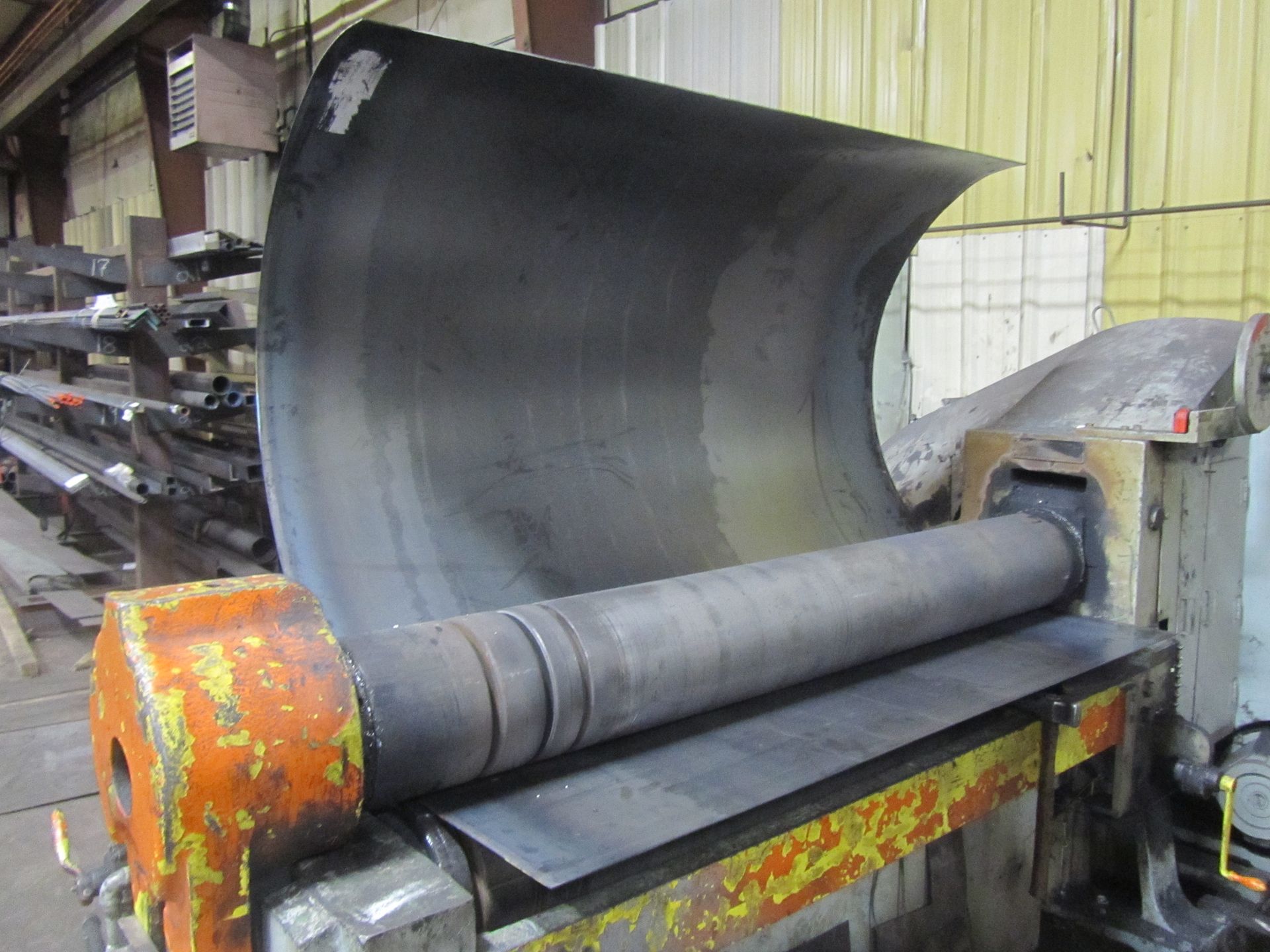 A large piece of metal is being rolled on a machine.