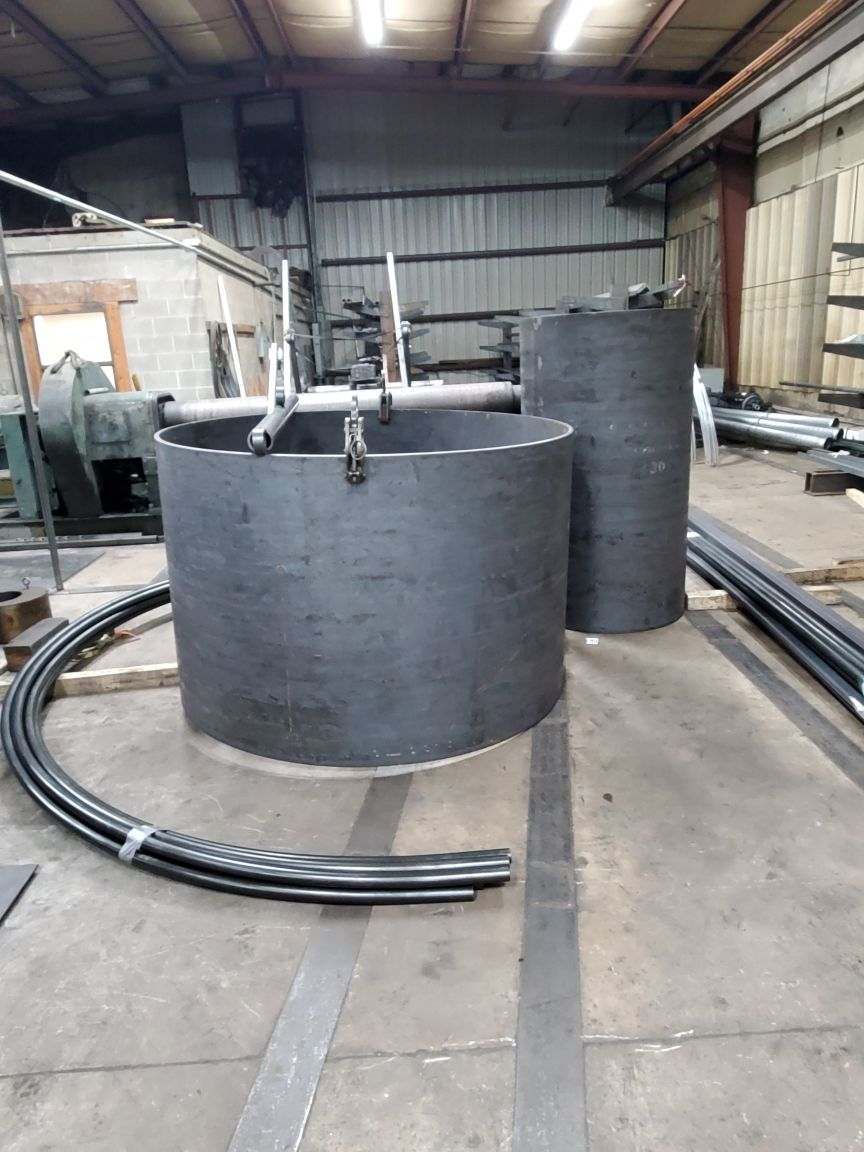 A bunch of metal pipes are sitting on the floor in a factory.