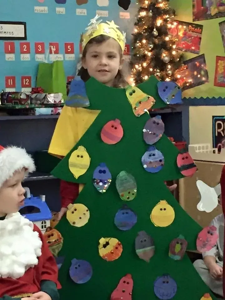 Child dressed as a decorated Christmas tree in a classroom holiday celebration